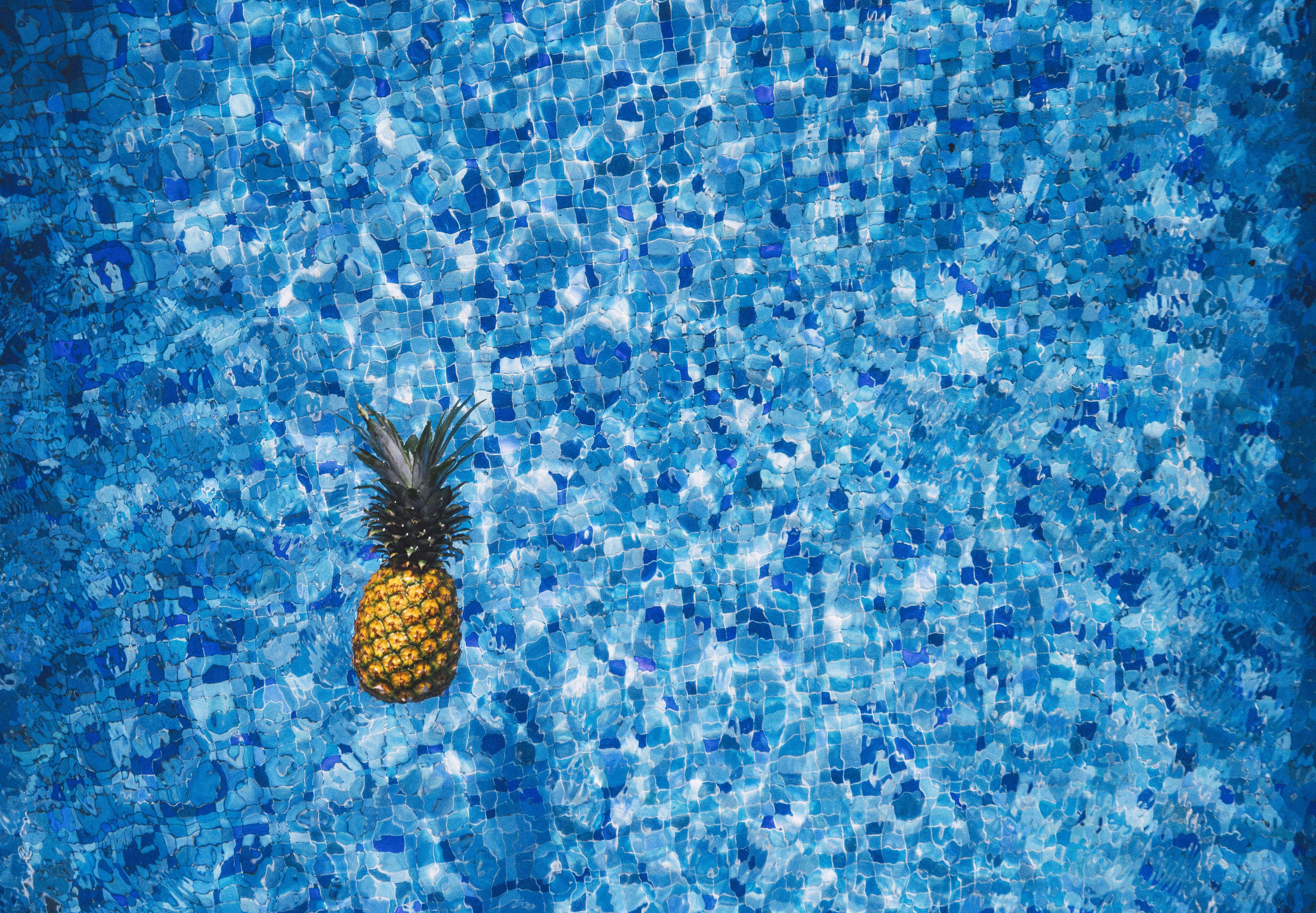 Pineapple floating in a blue tiled swimming pool 4K HD Wallpaper