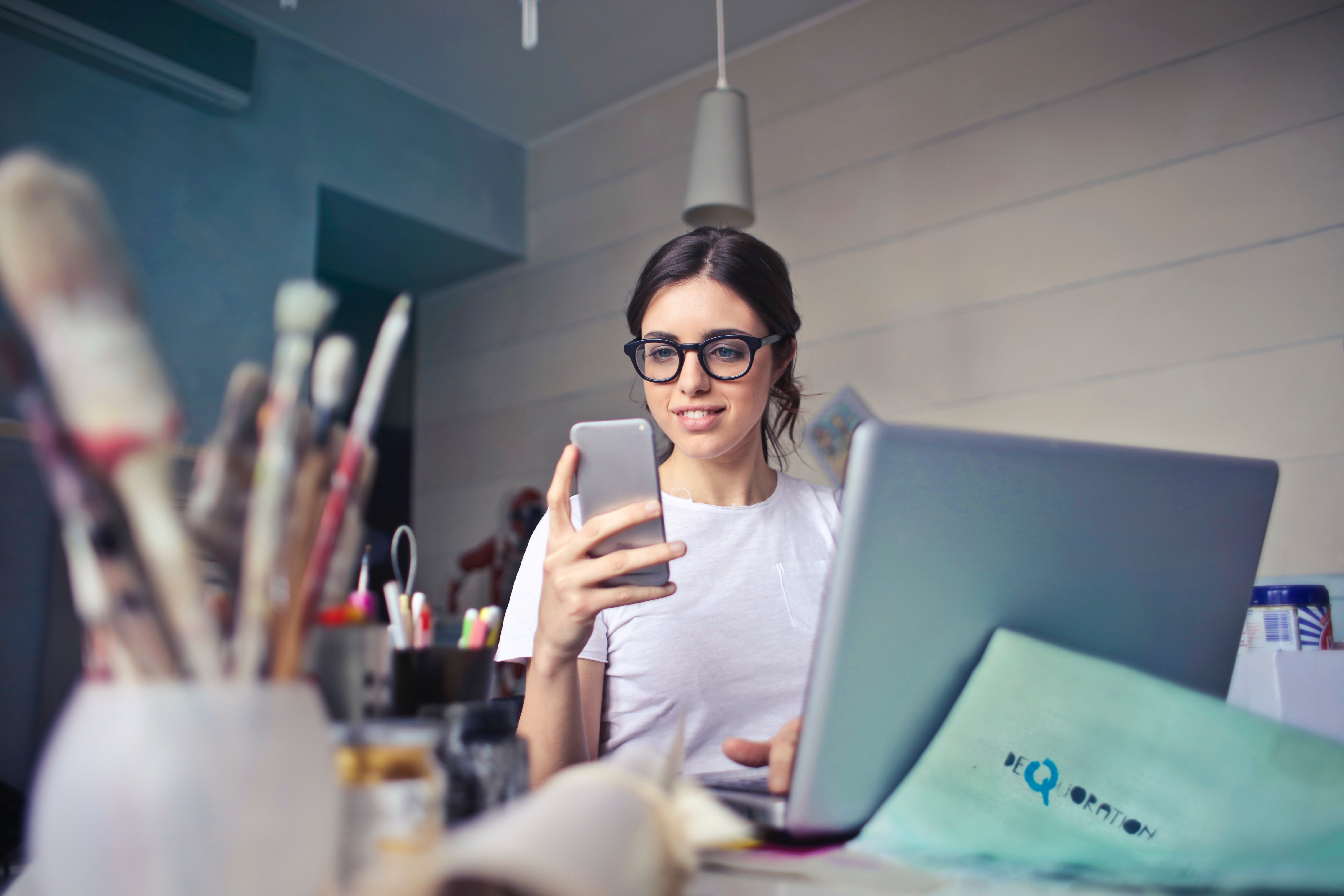 Woman in glasses working on laptop and smartphone HD Wallpaper