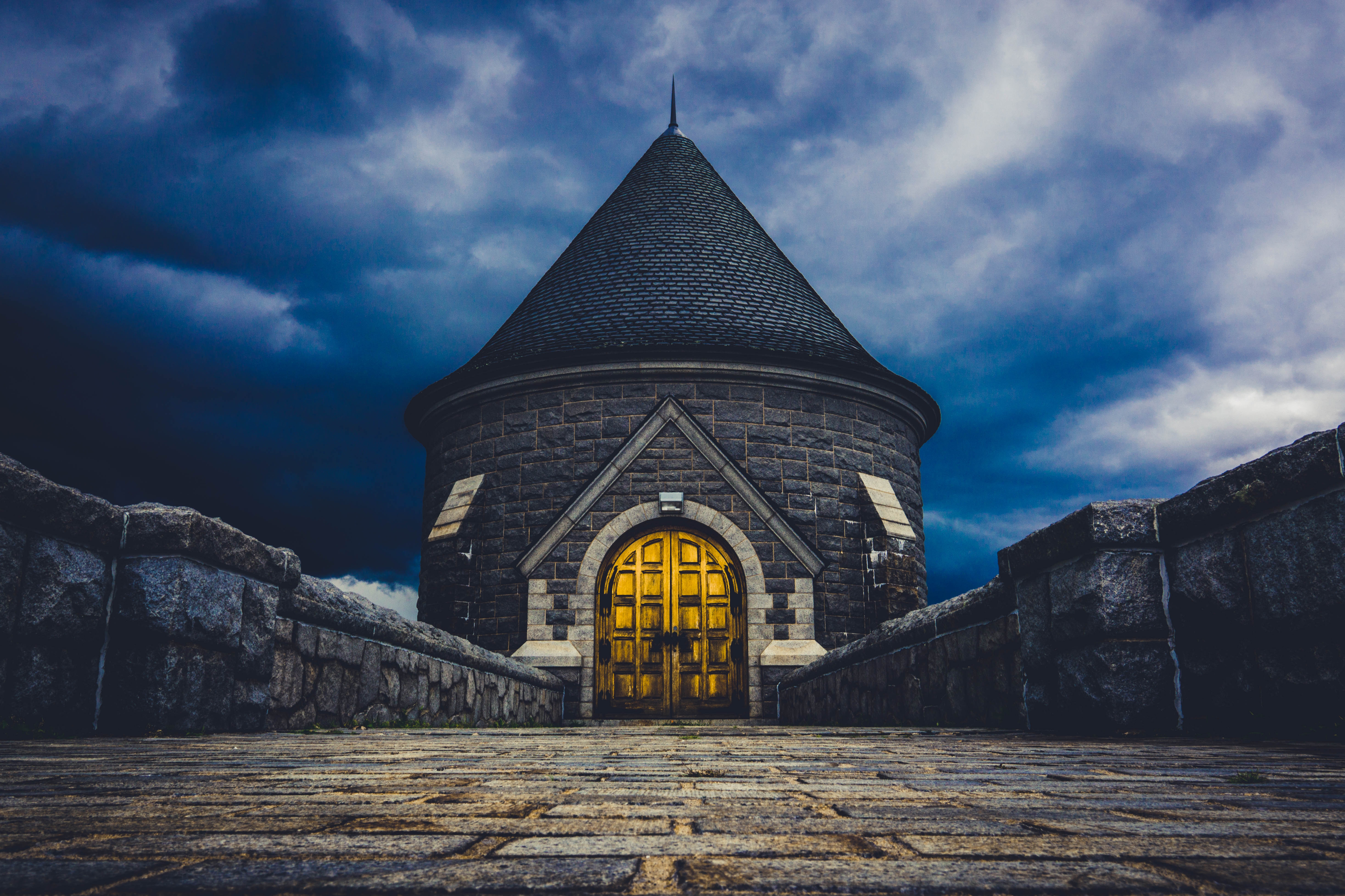 Stone tower with golden doors under stormy sky HD Wallpaper