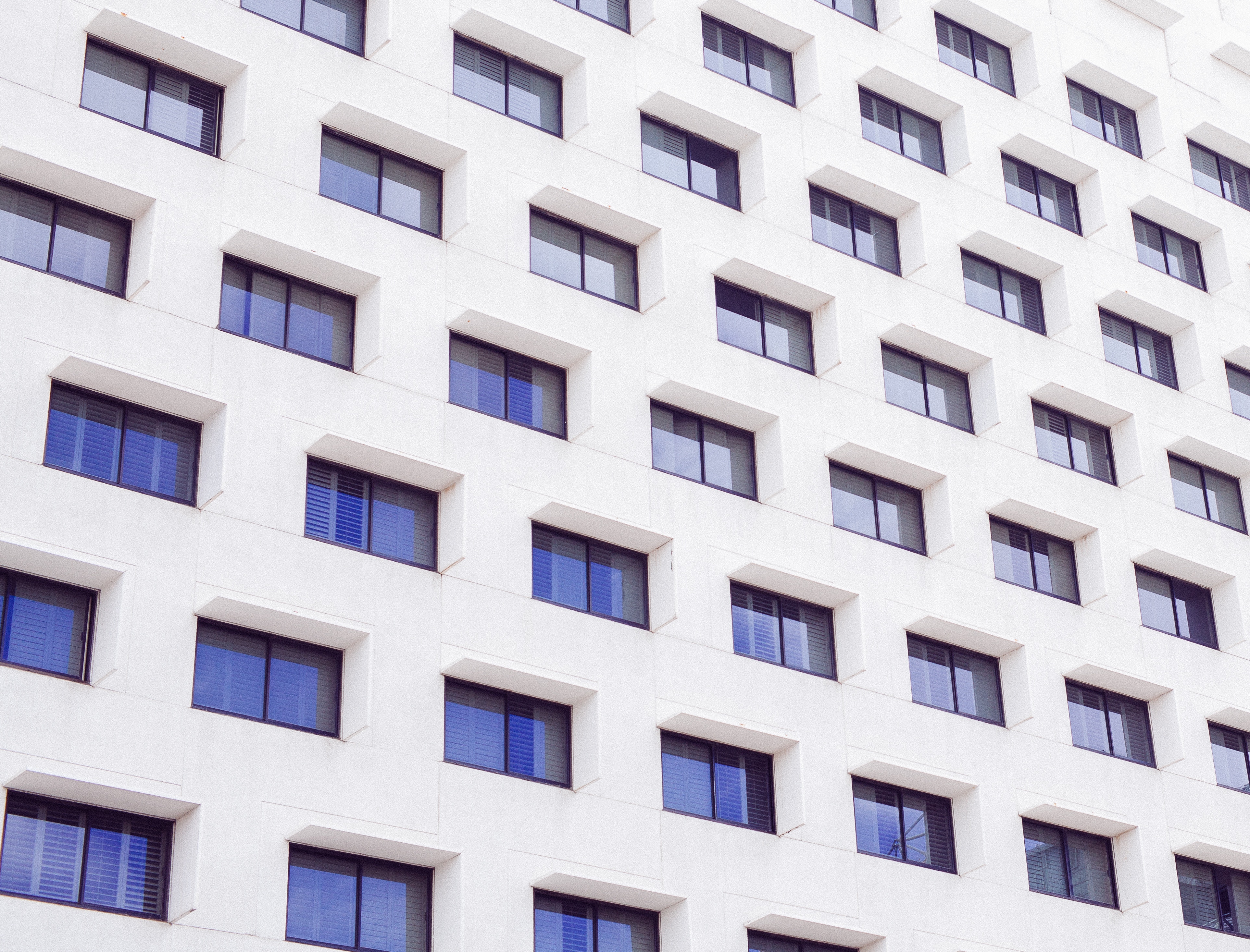 Minimalist facade of a white building with blue windows HD Wallpaper
