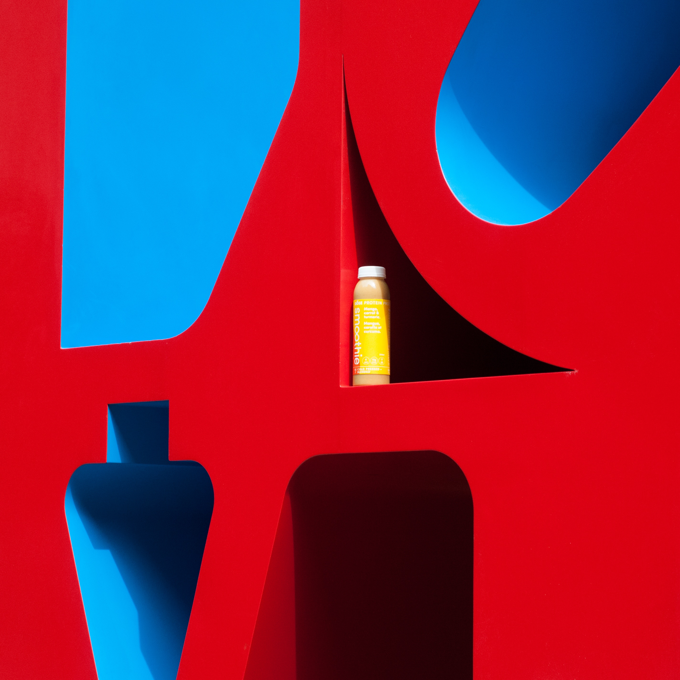Yellow smoothie bottle on red and blue abstract background HD Wallpaper