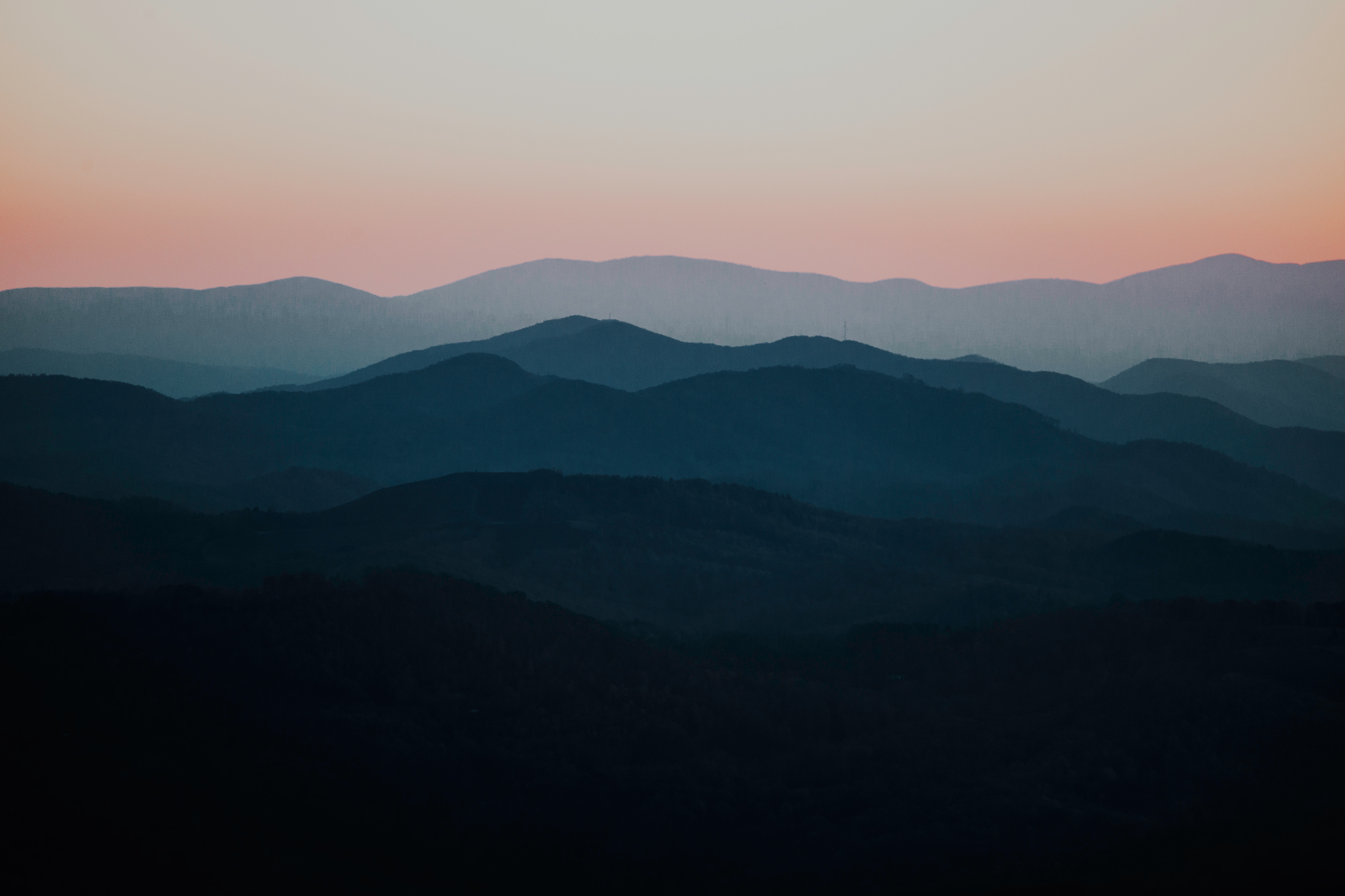 Layered mountain range at dusk with hazy sky HD Wallpaper