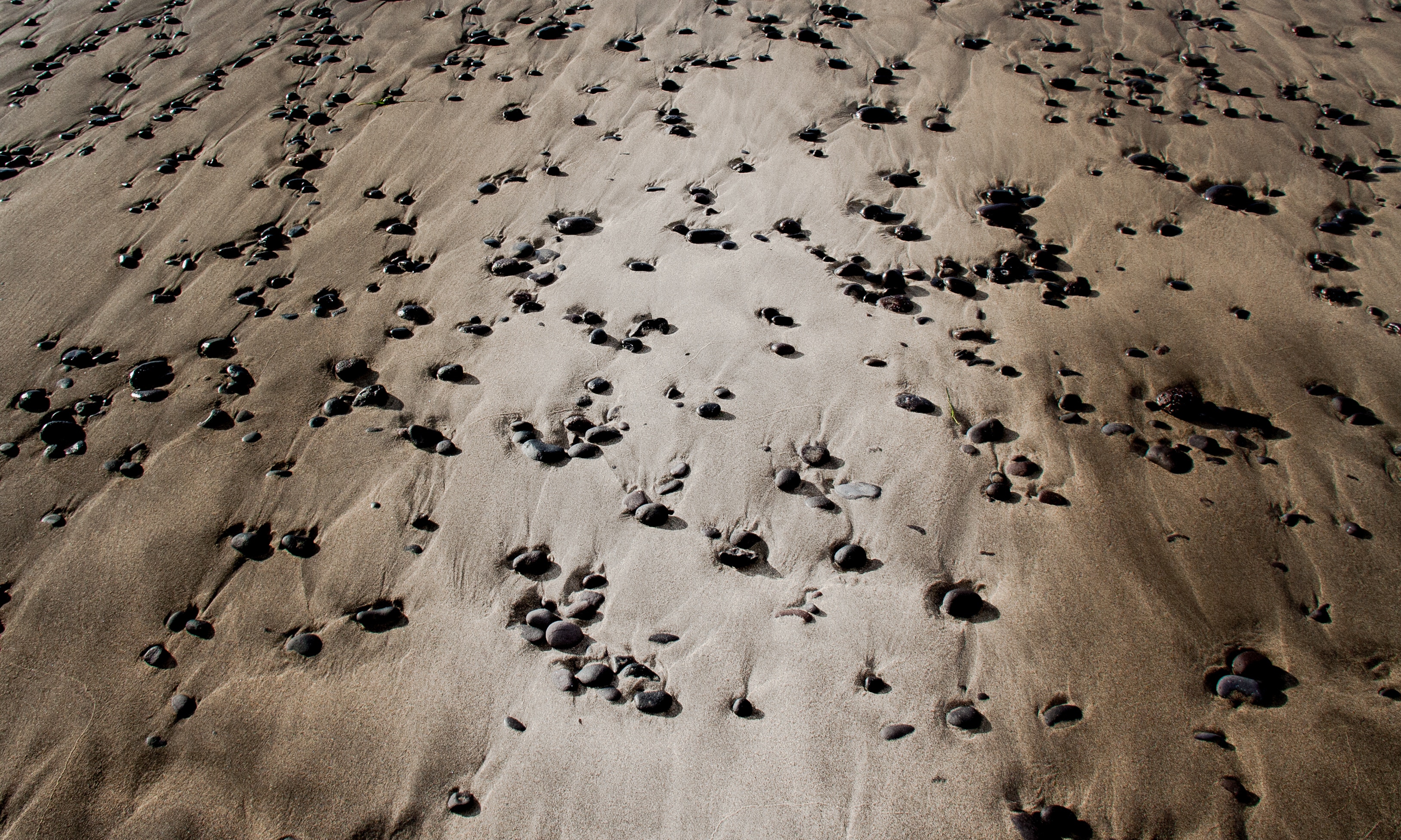 Pebbles and sand ripples on a dry riverbed HD Wallpaper