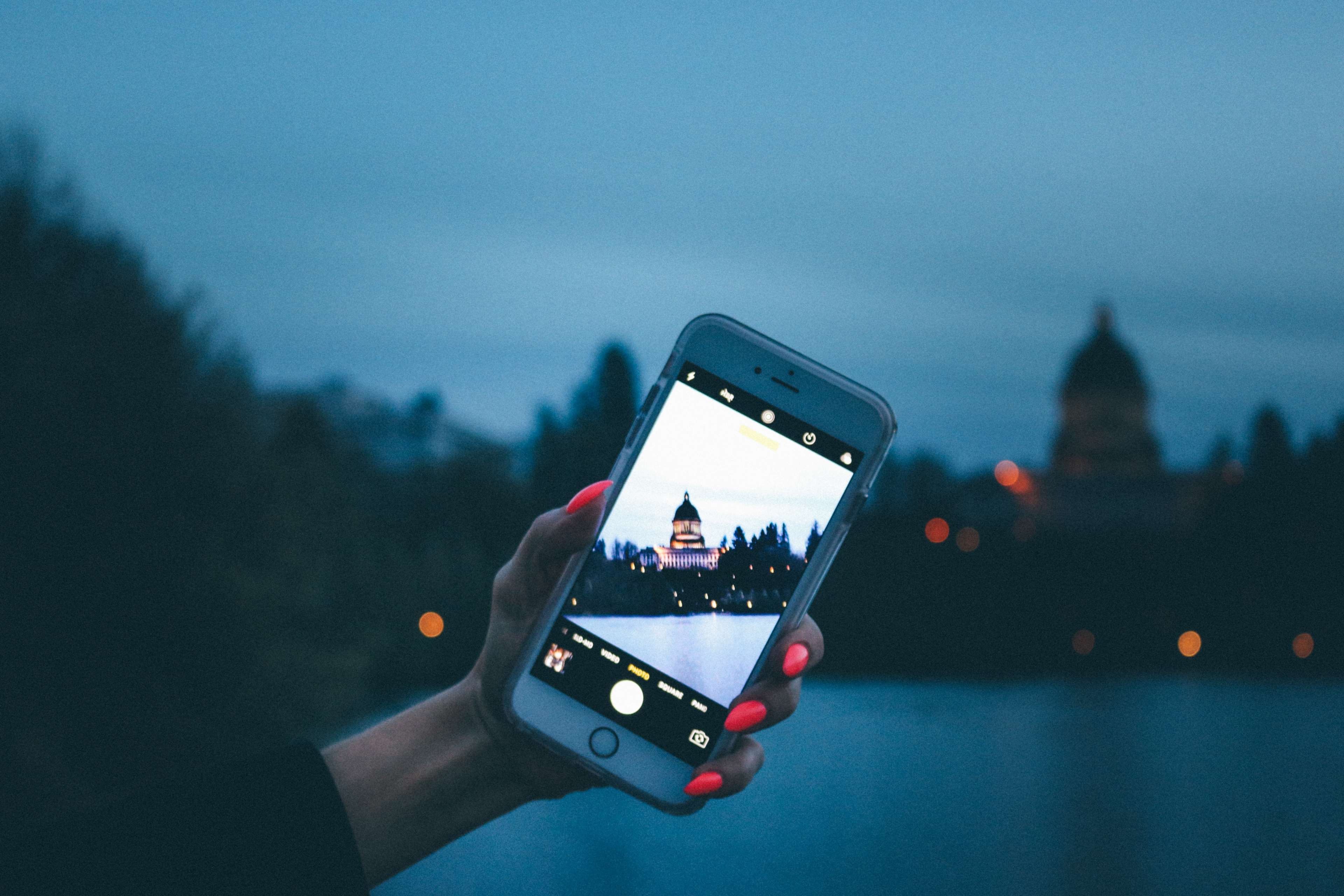 Hand holding iPhone taking picture of capitol building at dusk HD Wallpaper