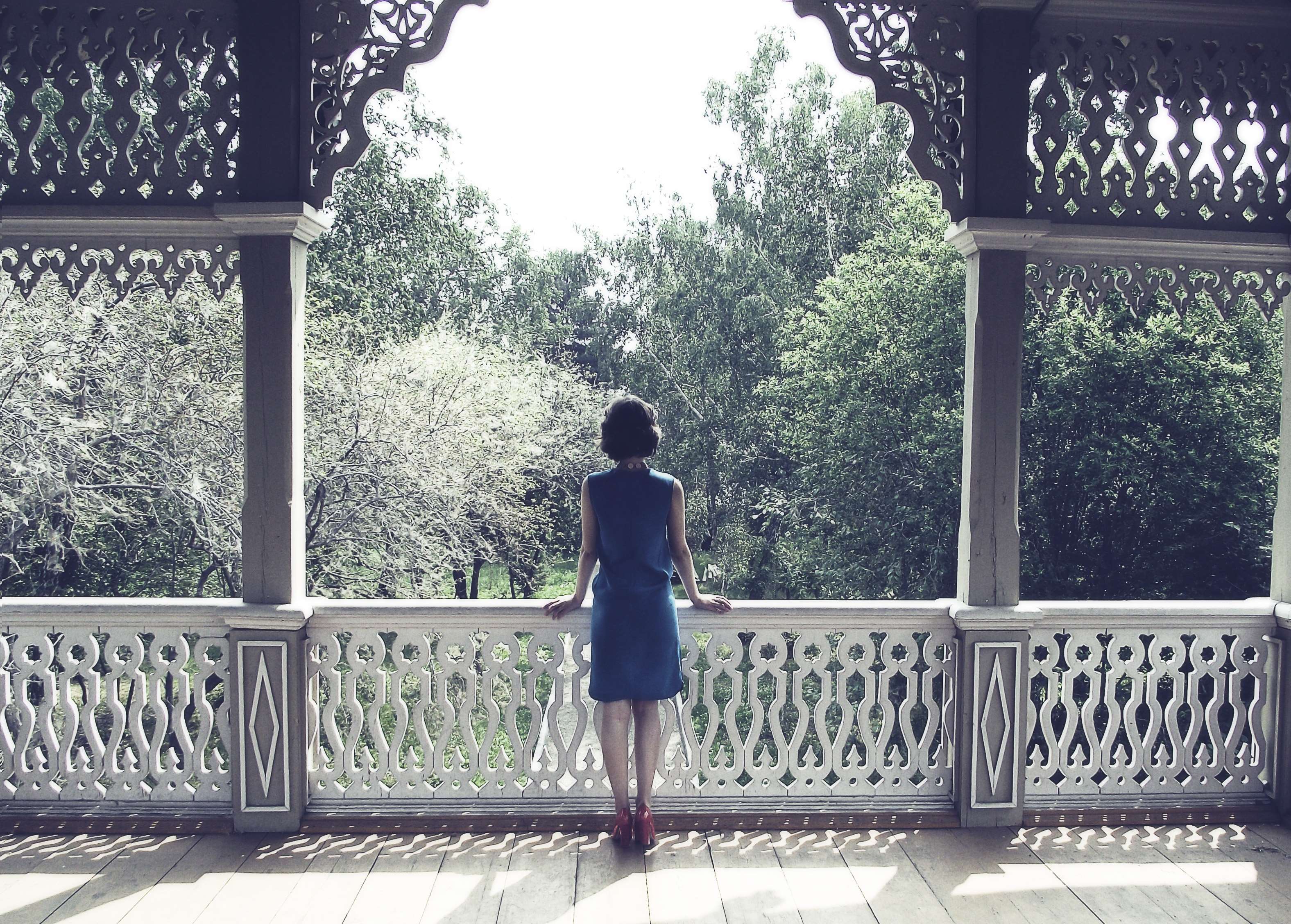 Woman in blue dress on a balcony overlooking trees HD Wallpaper