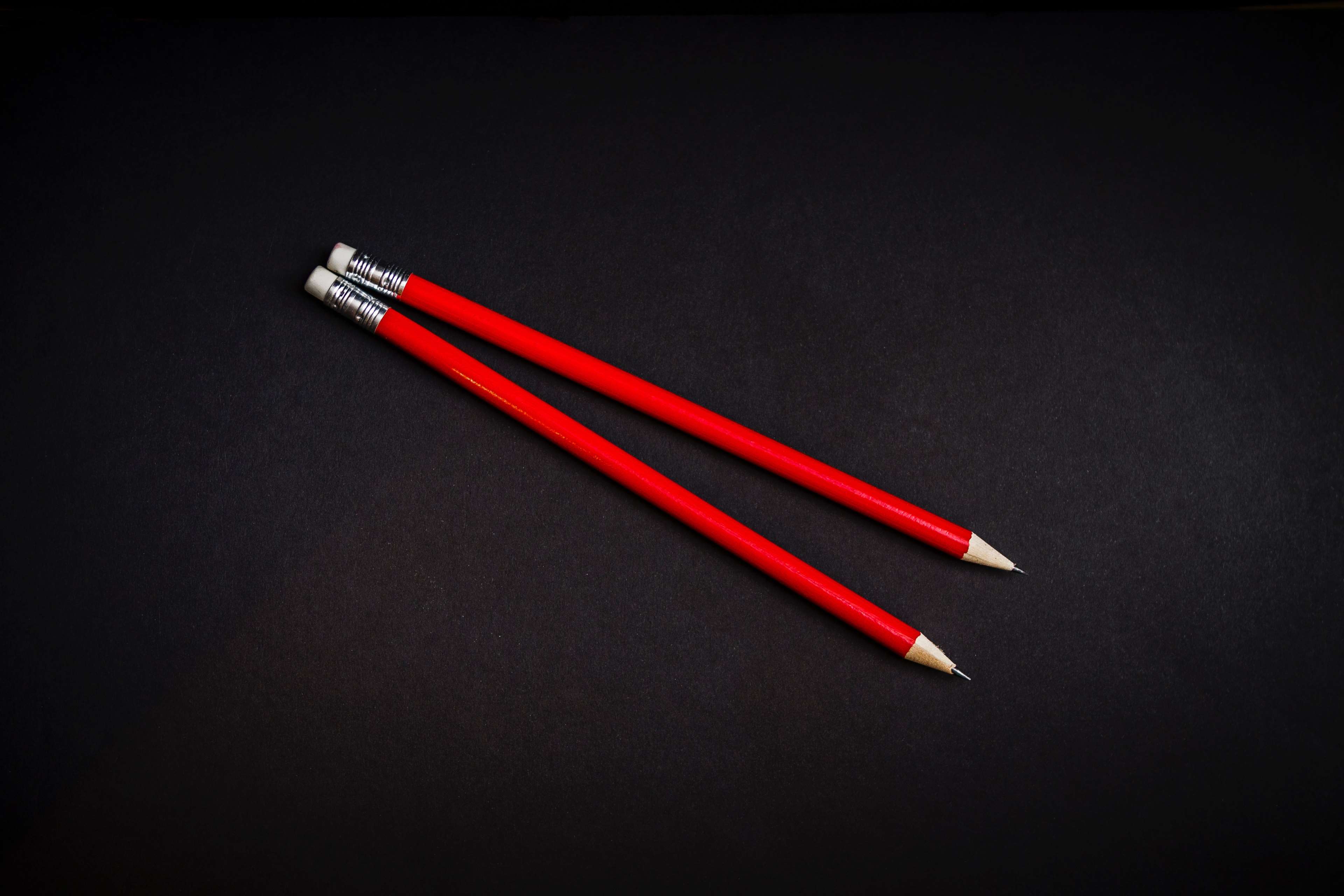 Two red pencils on a black surface HD Wallpaper