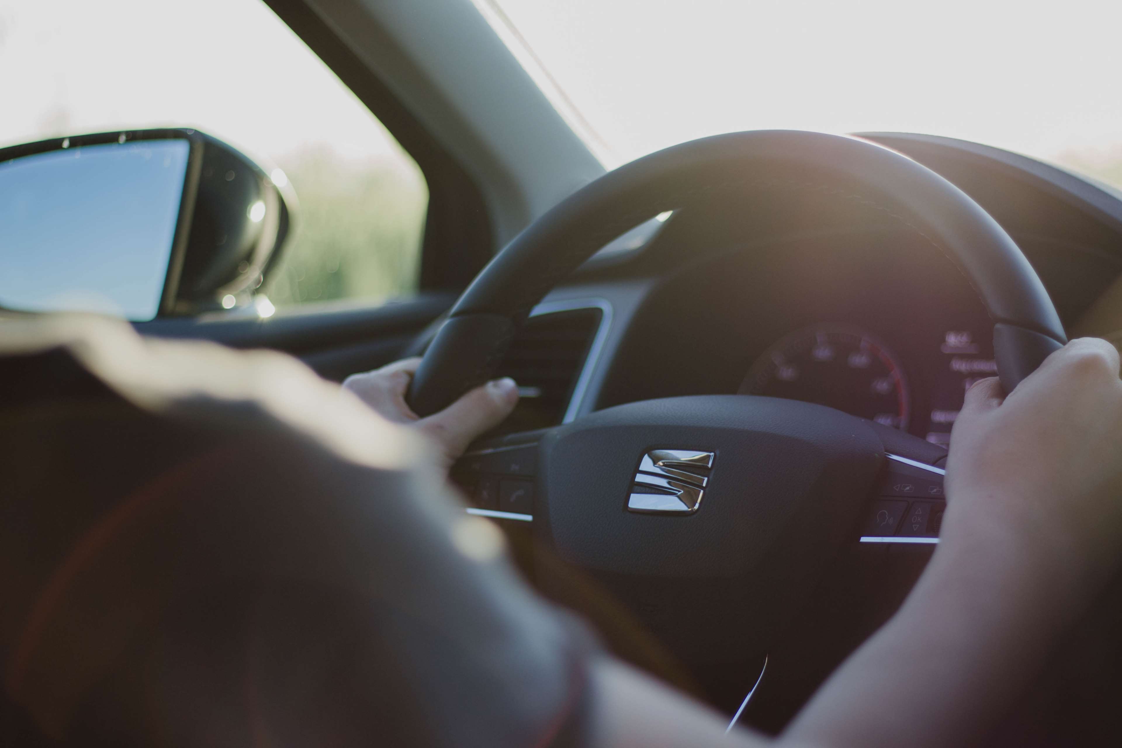 Person driving a car with hands on steering wheel HD Wallpaper