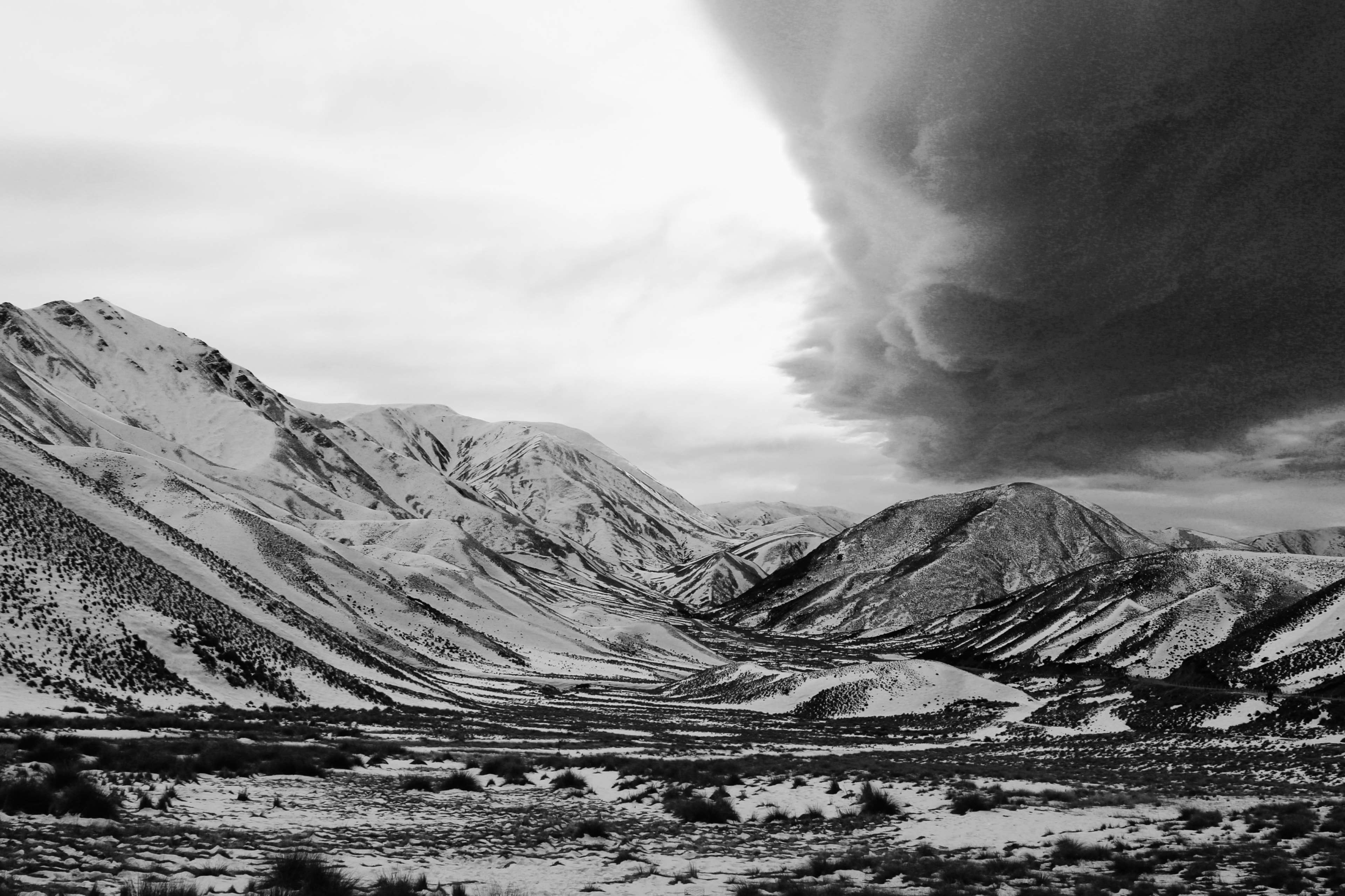 Snow-capped mountains under dark storm clouds in New Zealand 4K HD Wallpaper