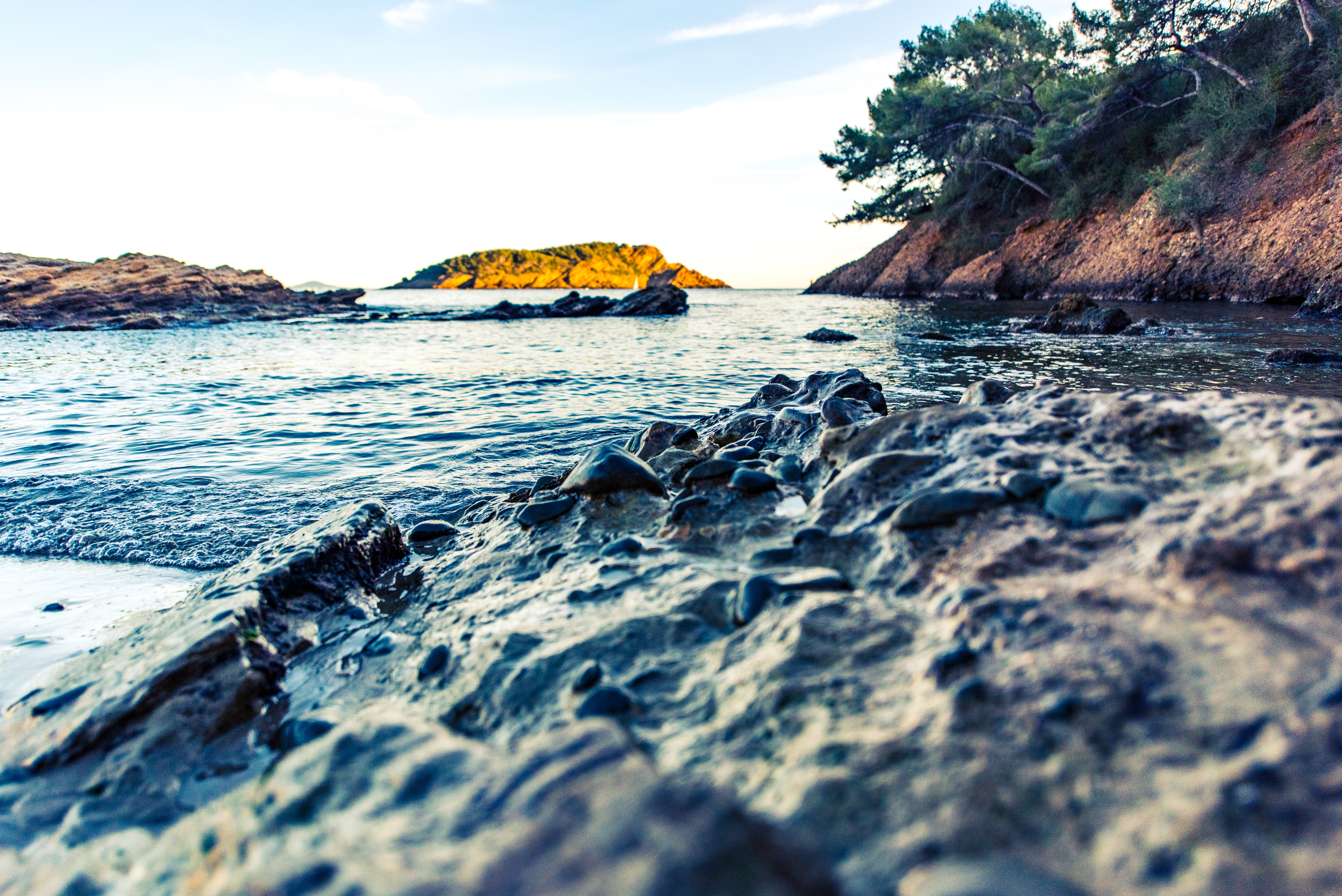 Close-up of rocks on a beach with the sea and an island in the background HD Wallpaper