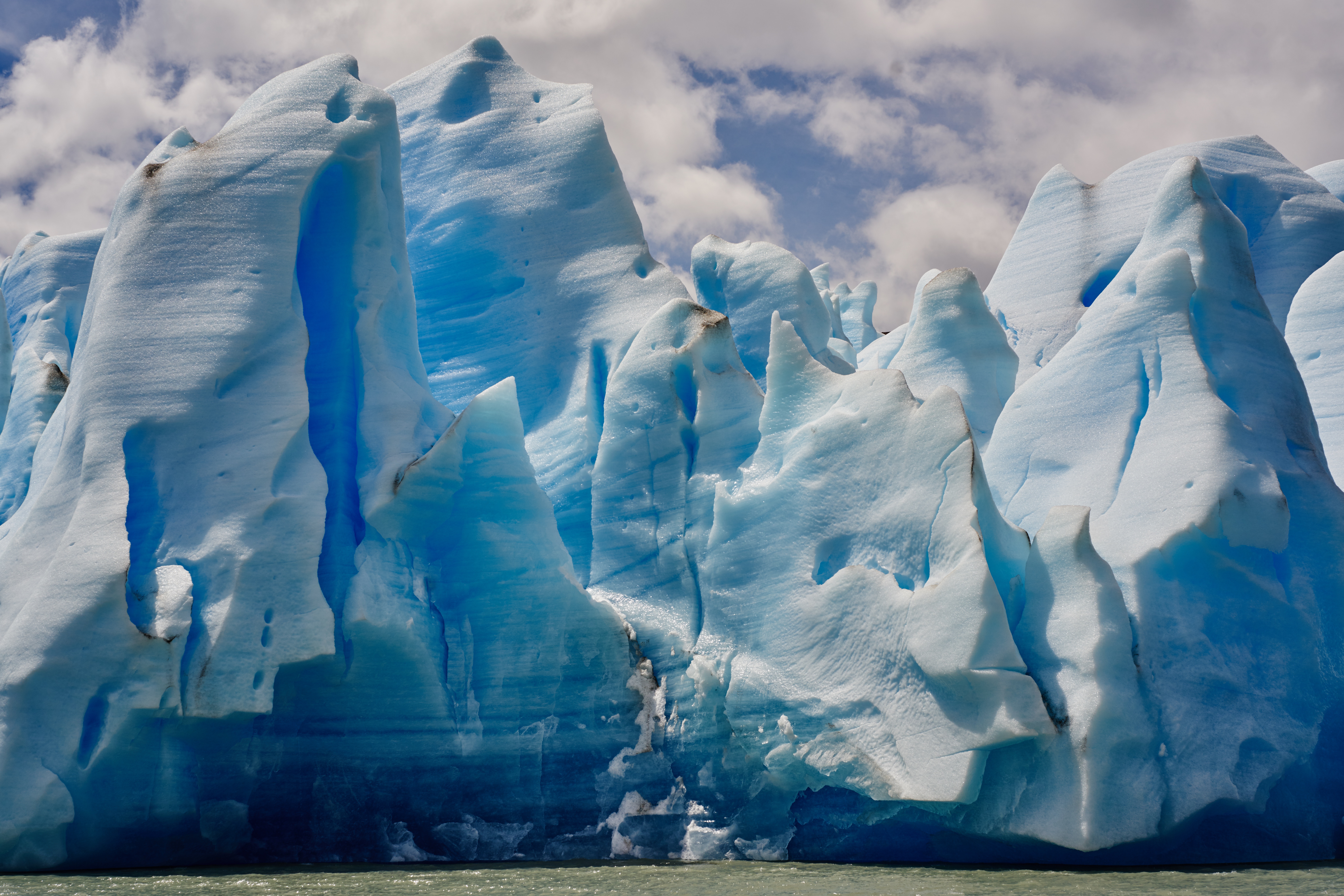 Blue glacier ice formations under a cloudy sky HD Wallpaper
