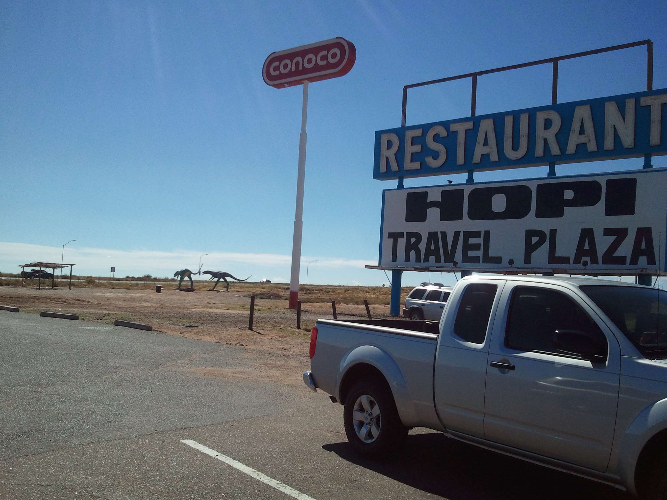 Conoco and Hopi Travel Plaza sign with dinosaur statues HD Wallpaper