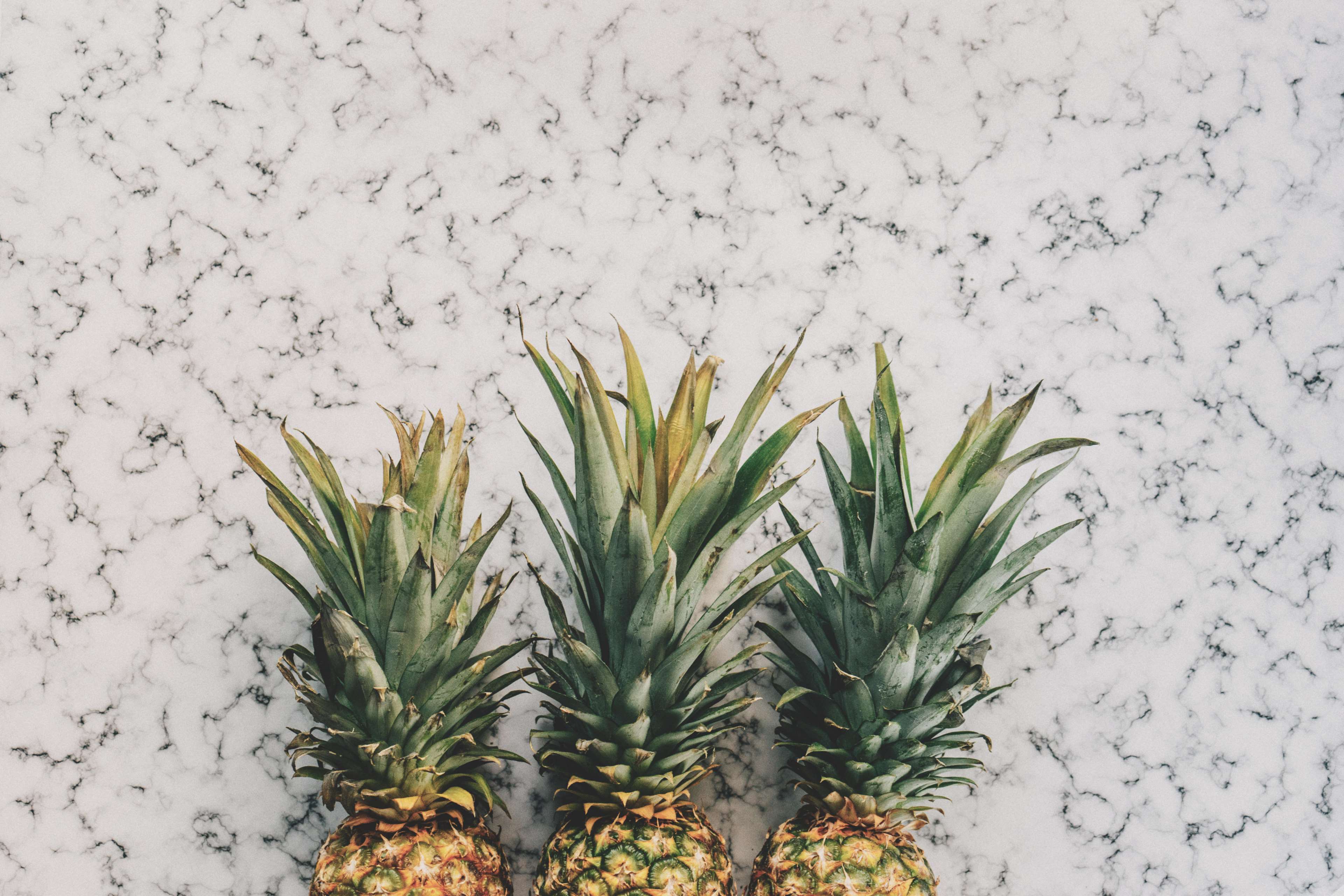 Three pineapples on a marble surface HD Wallpaper