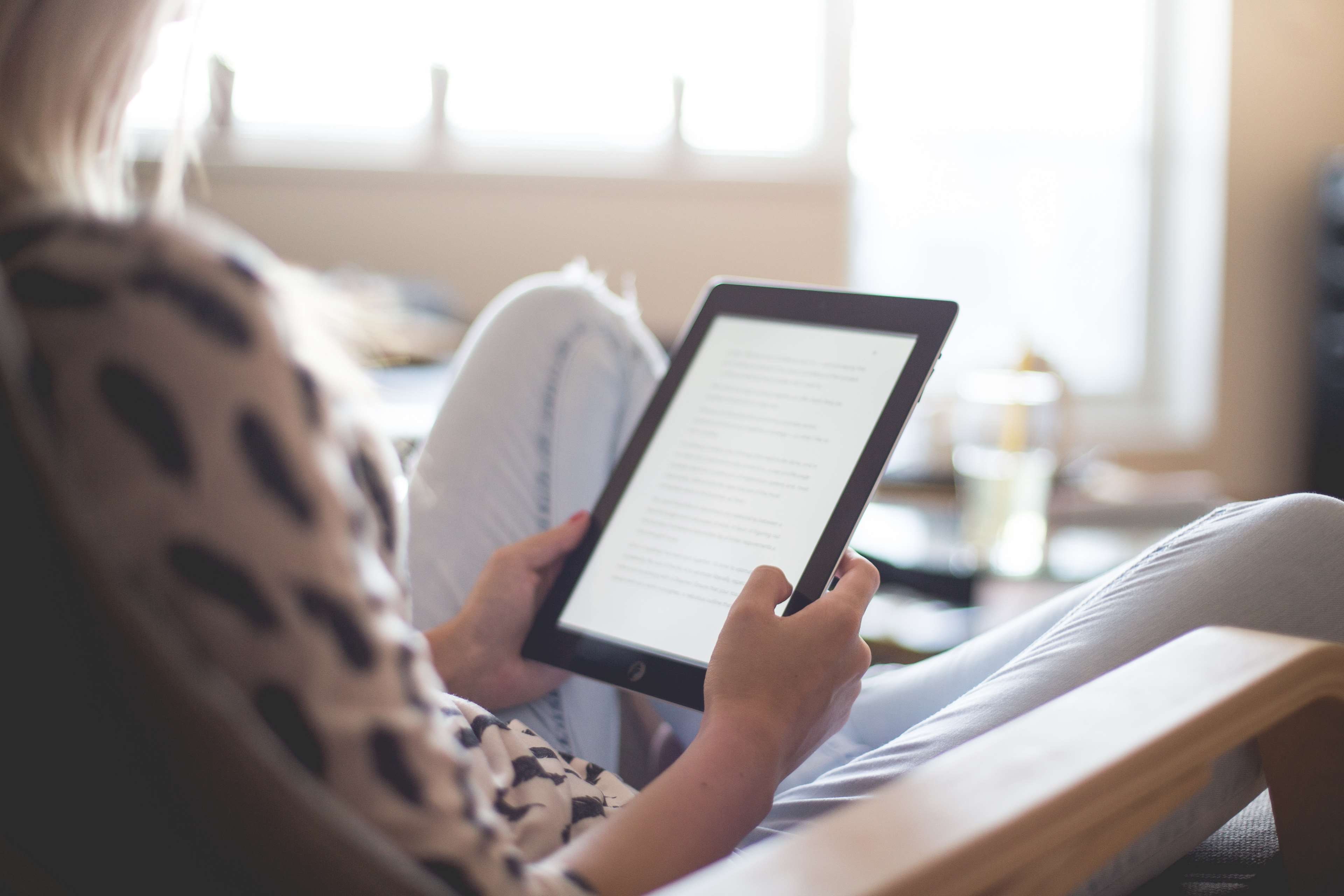 Woman reading on a tablet in a living room HD Wallpaper