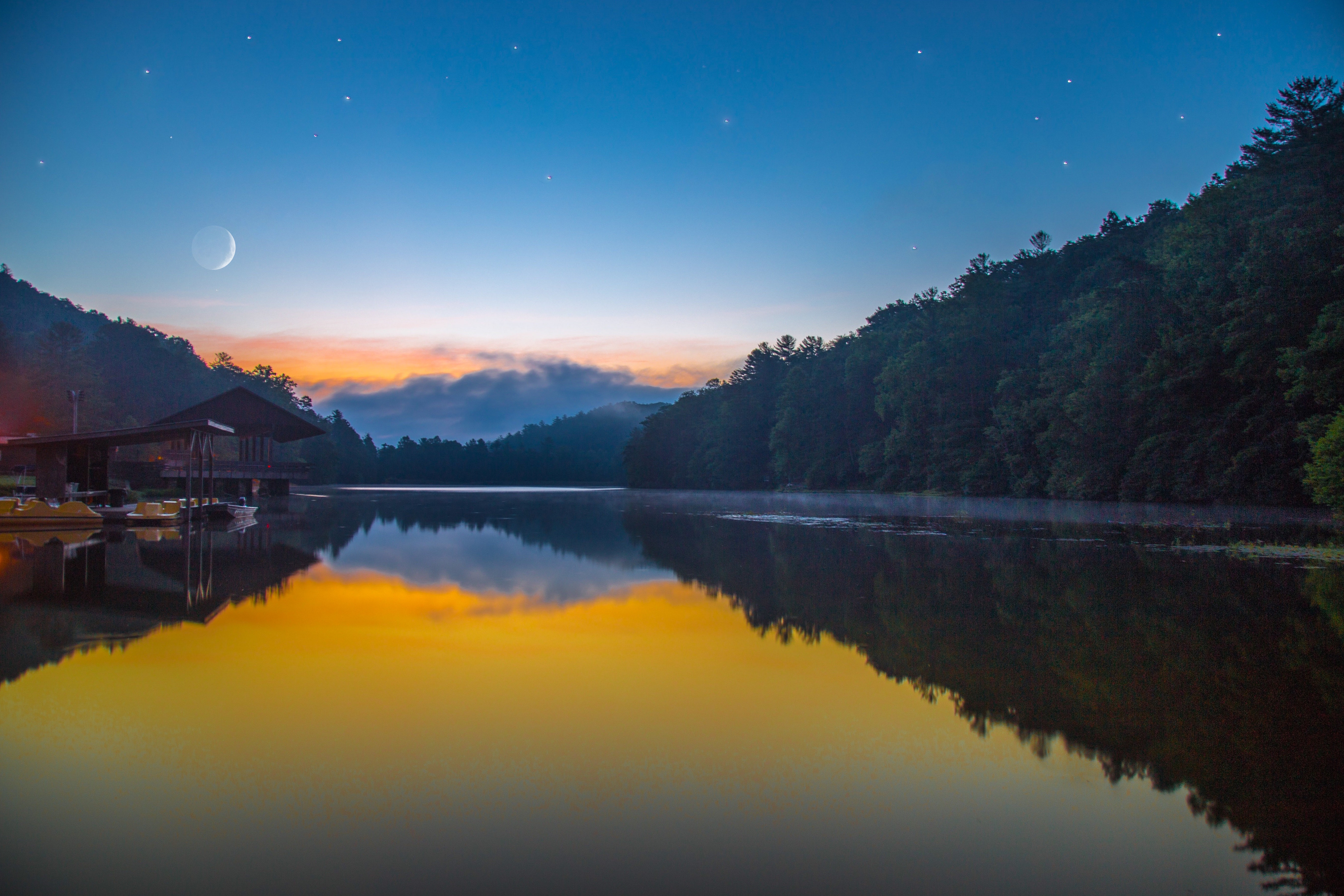 Crescent moon over a calm lake with a dock and forest HD Wallpaper