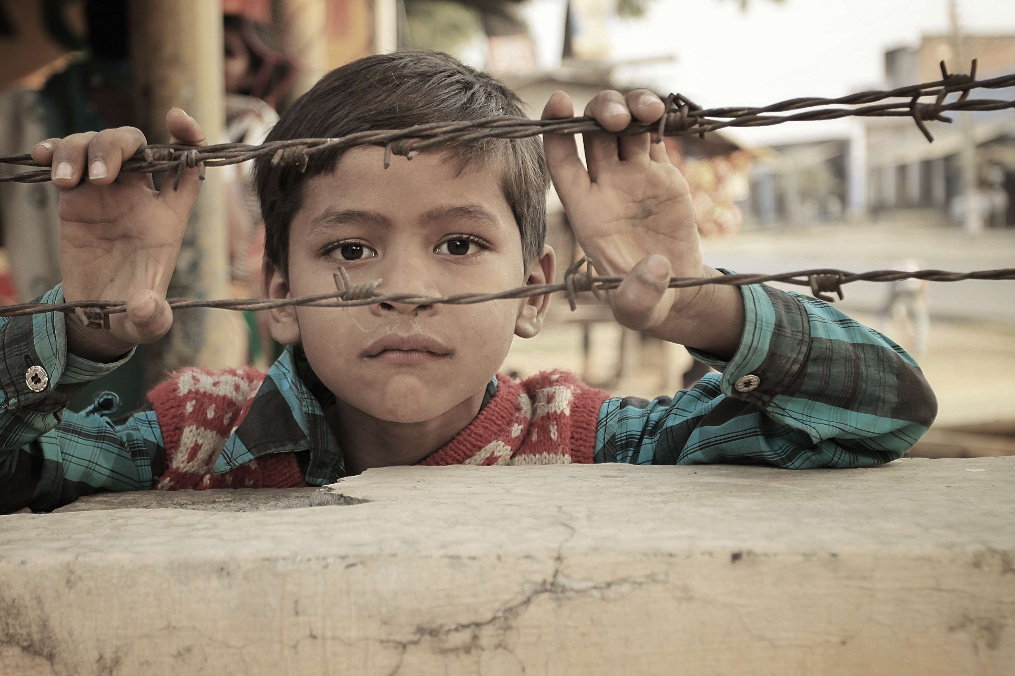 Young Indian boy behind barbed wire HD Wallpaper