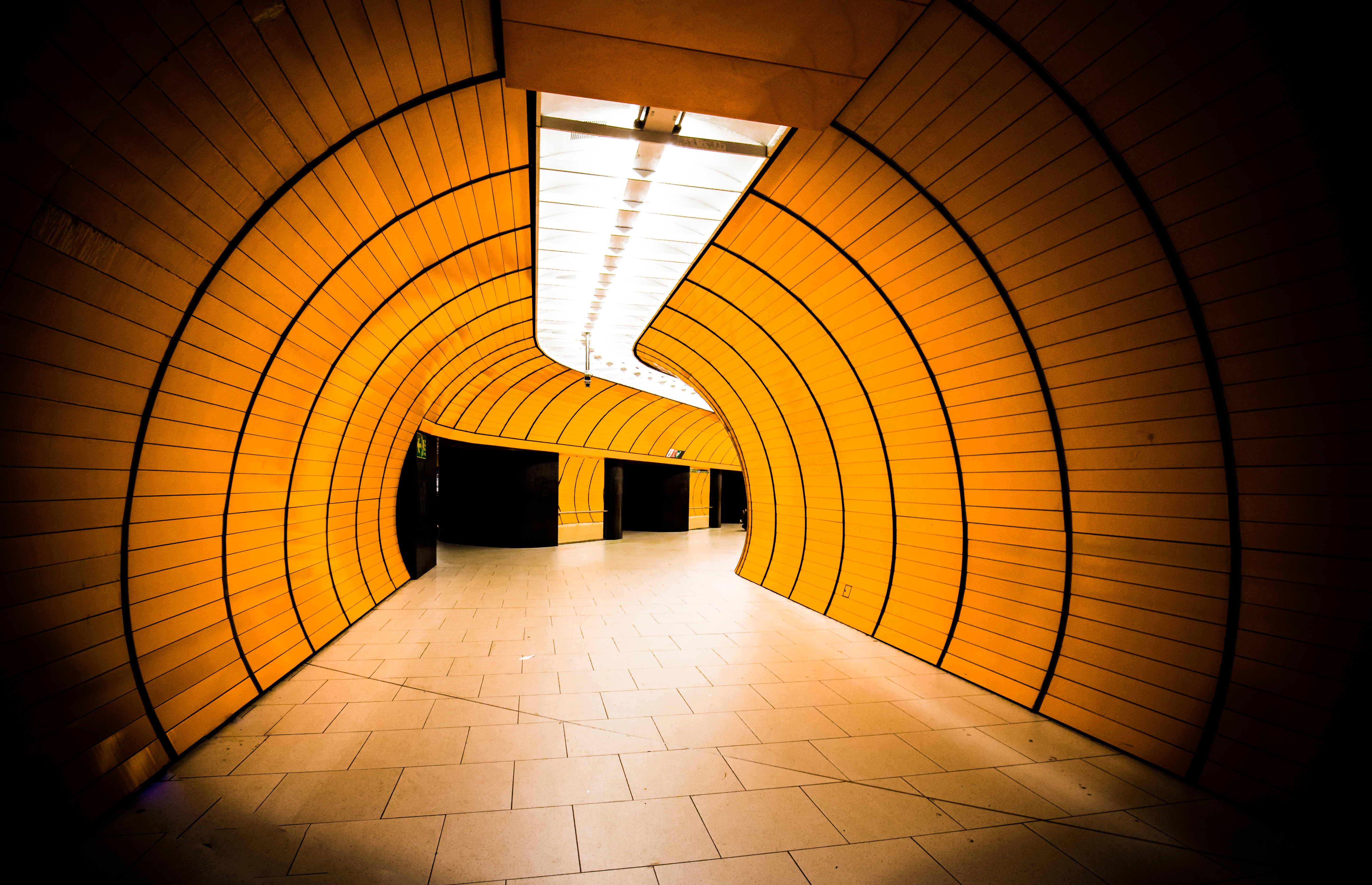 Modern orange tunnel with curved walls and ceiling lights HD Wallpaper