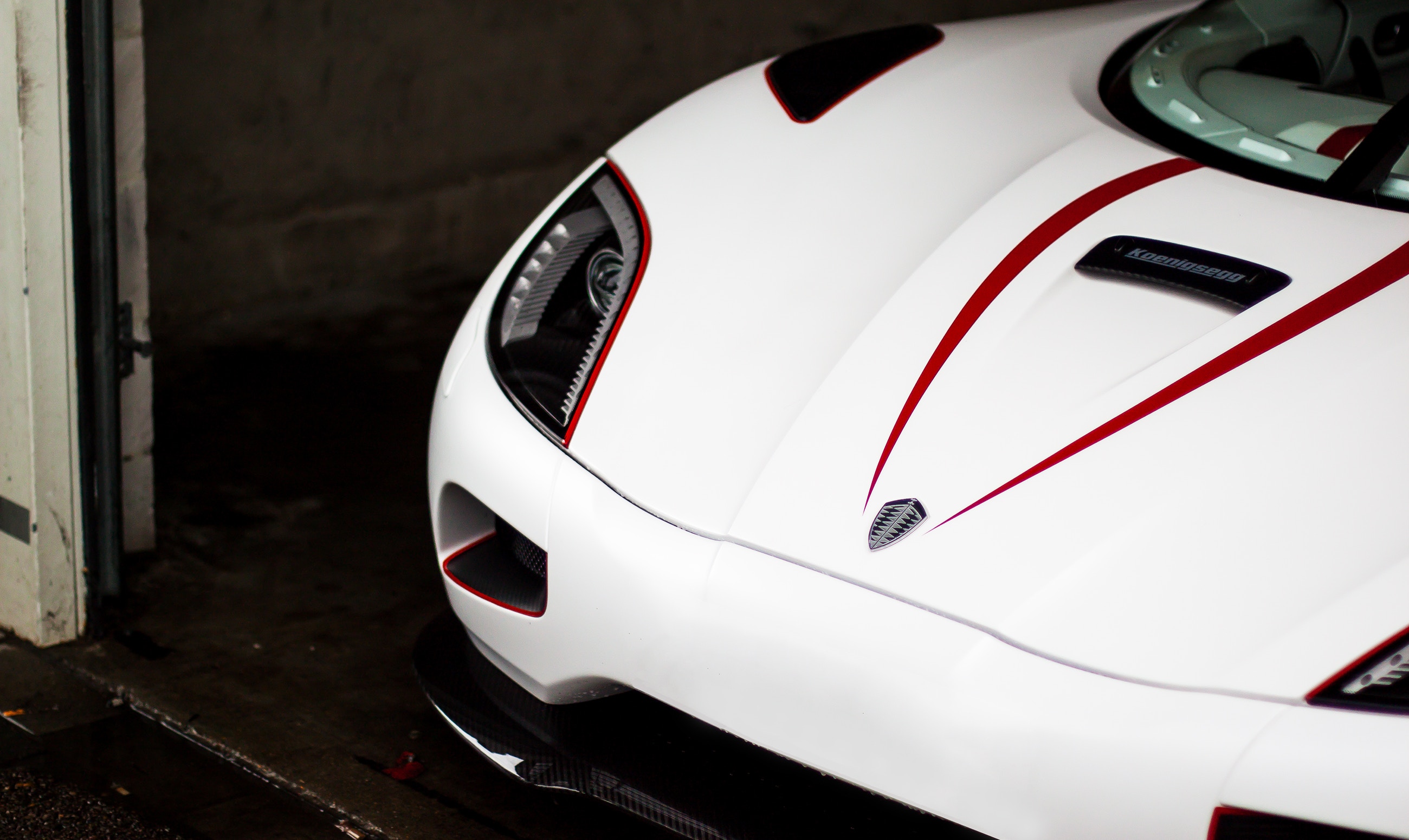 White Koenigsegg sports car with red accents in garage HD Wallpaper