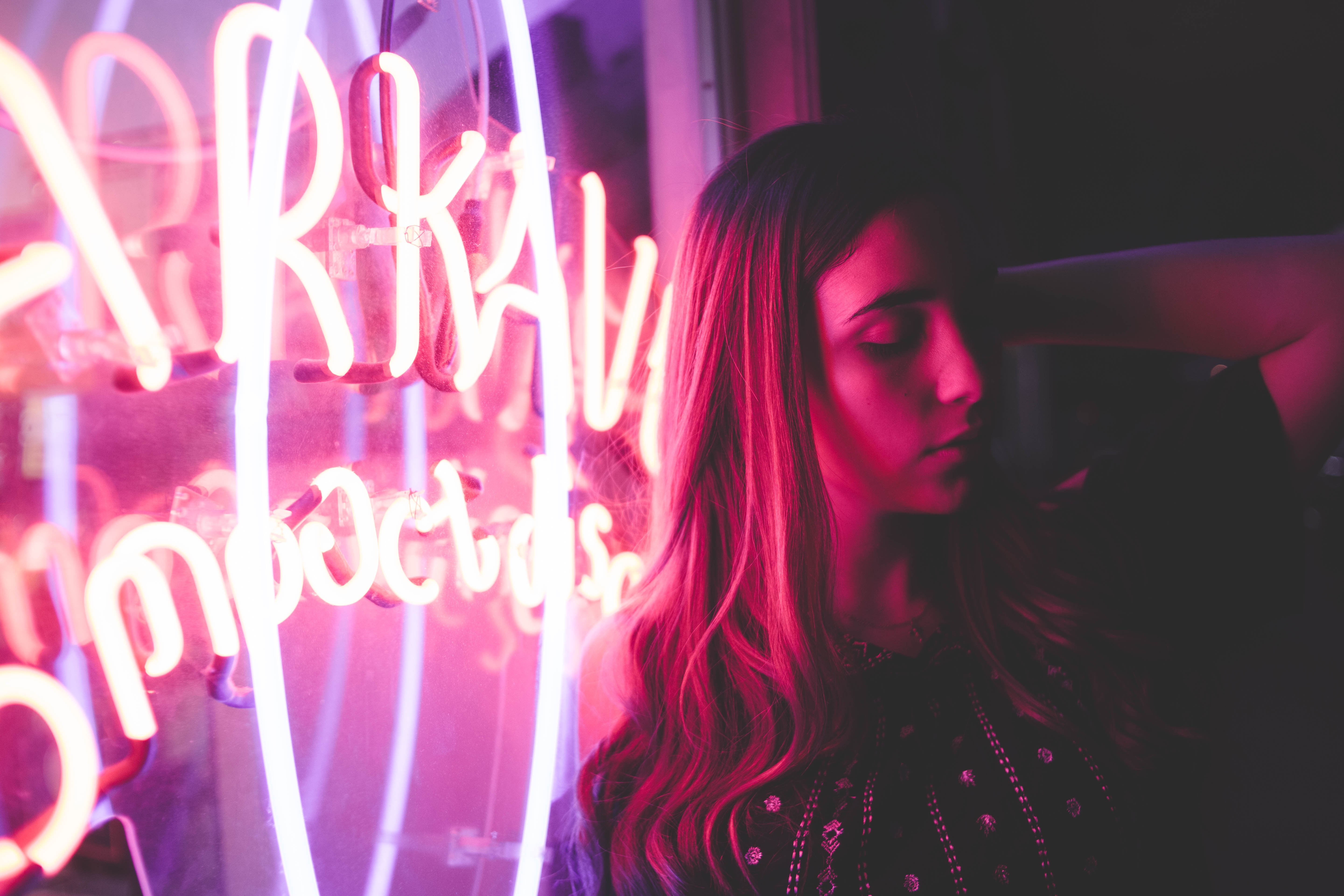 Woman illuminated by pink neon sign HD Wallpaper