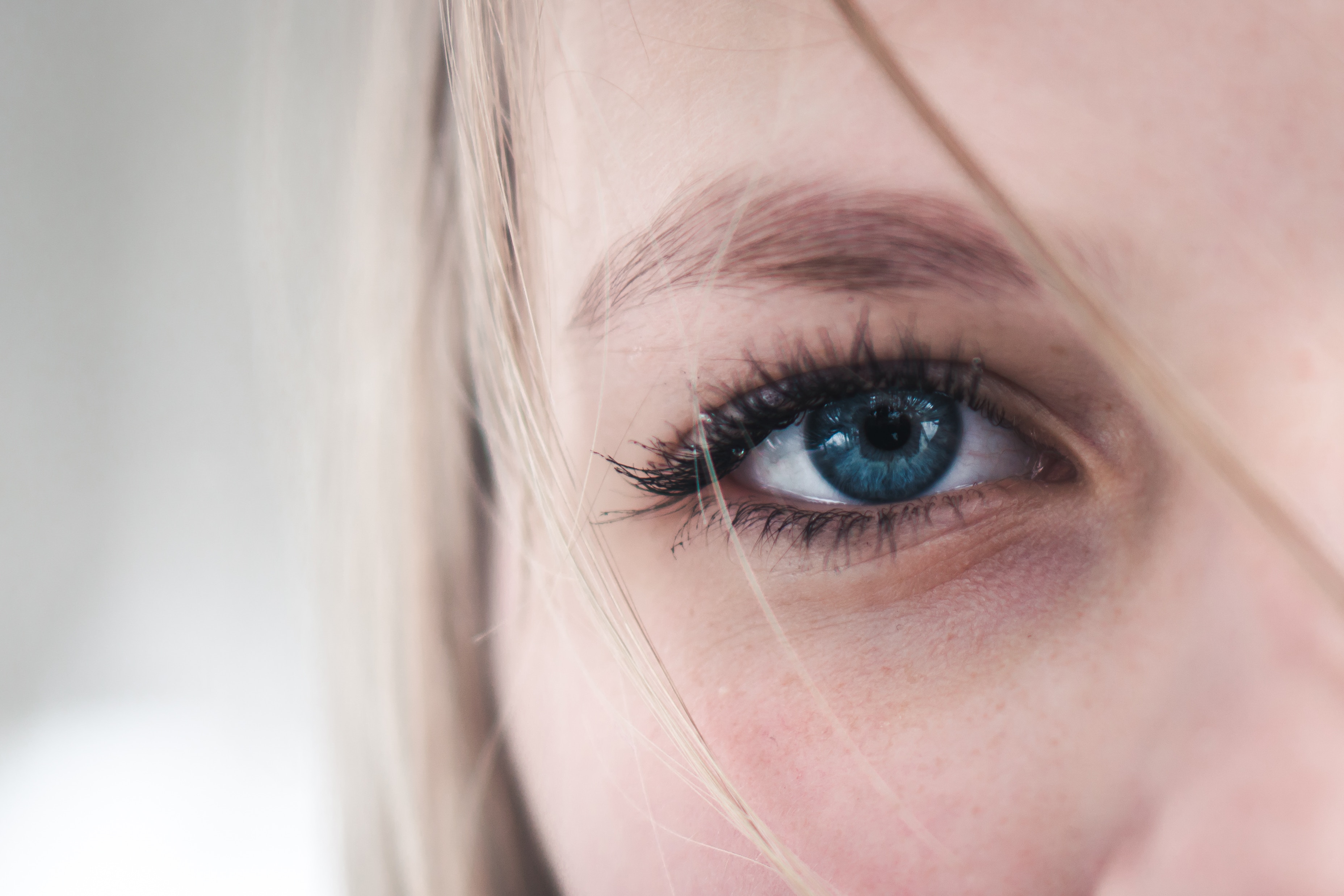 Close up of a woman's blue eye with blonde hair HD Wallpaper