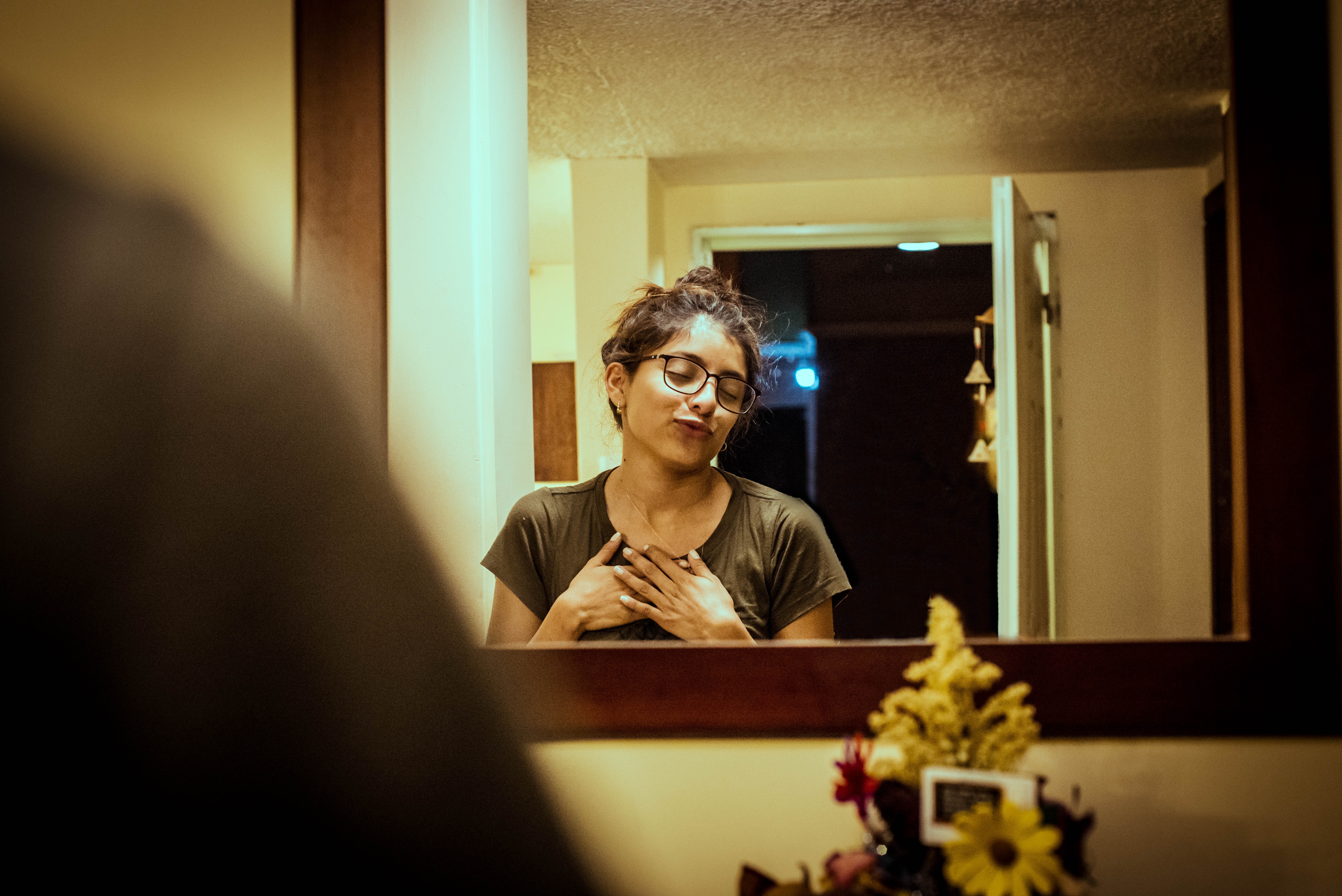 Woman with glasses touching her chest in a mirror HD Wallpaper