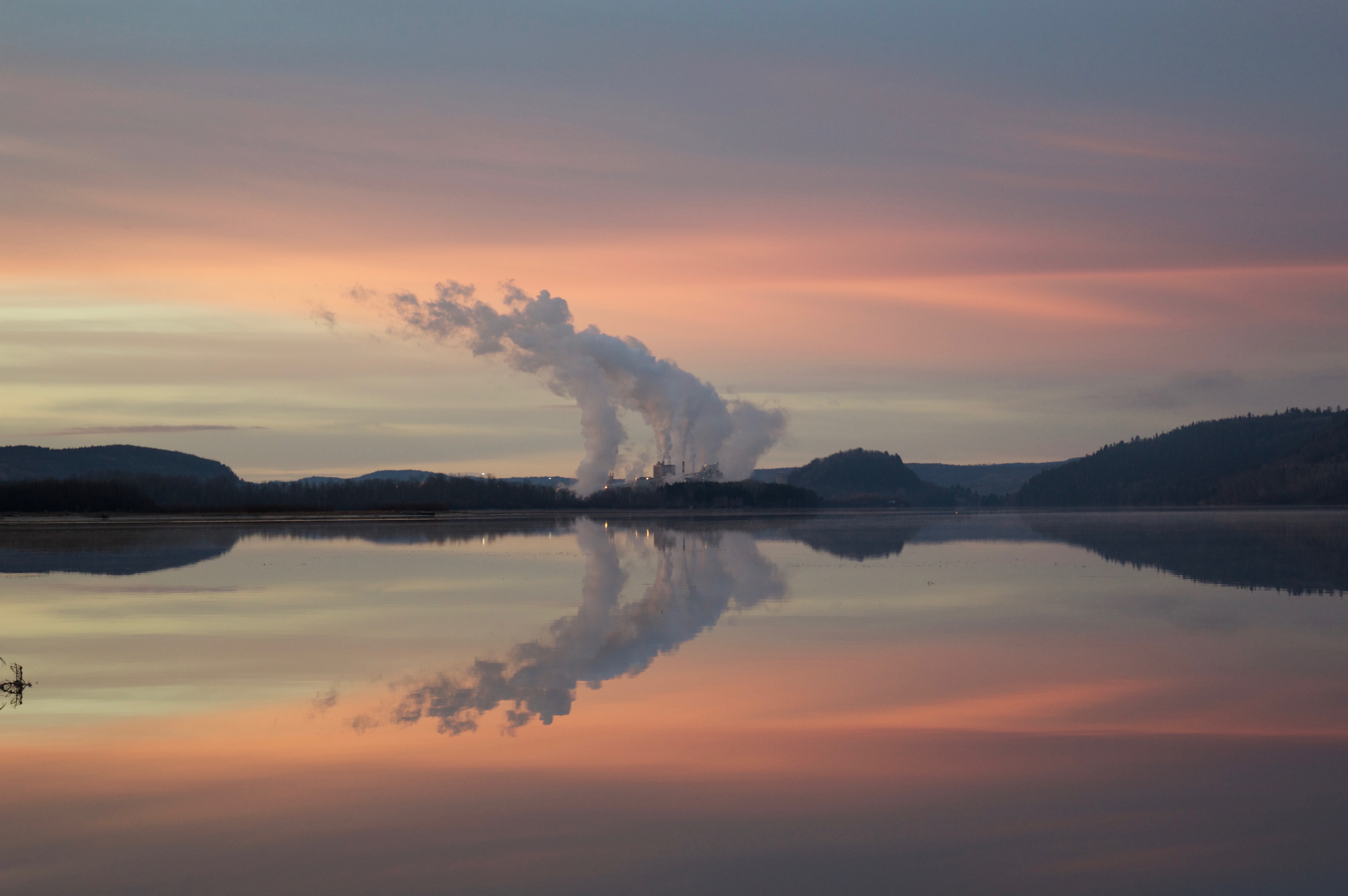 Factory smoke reflecting on a lake at dawn HD Wallpaper