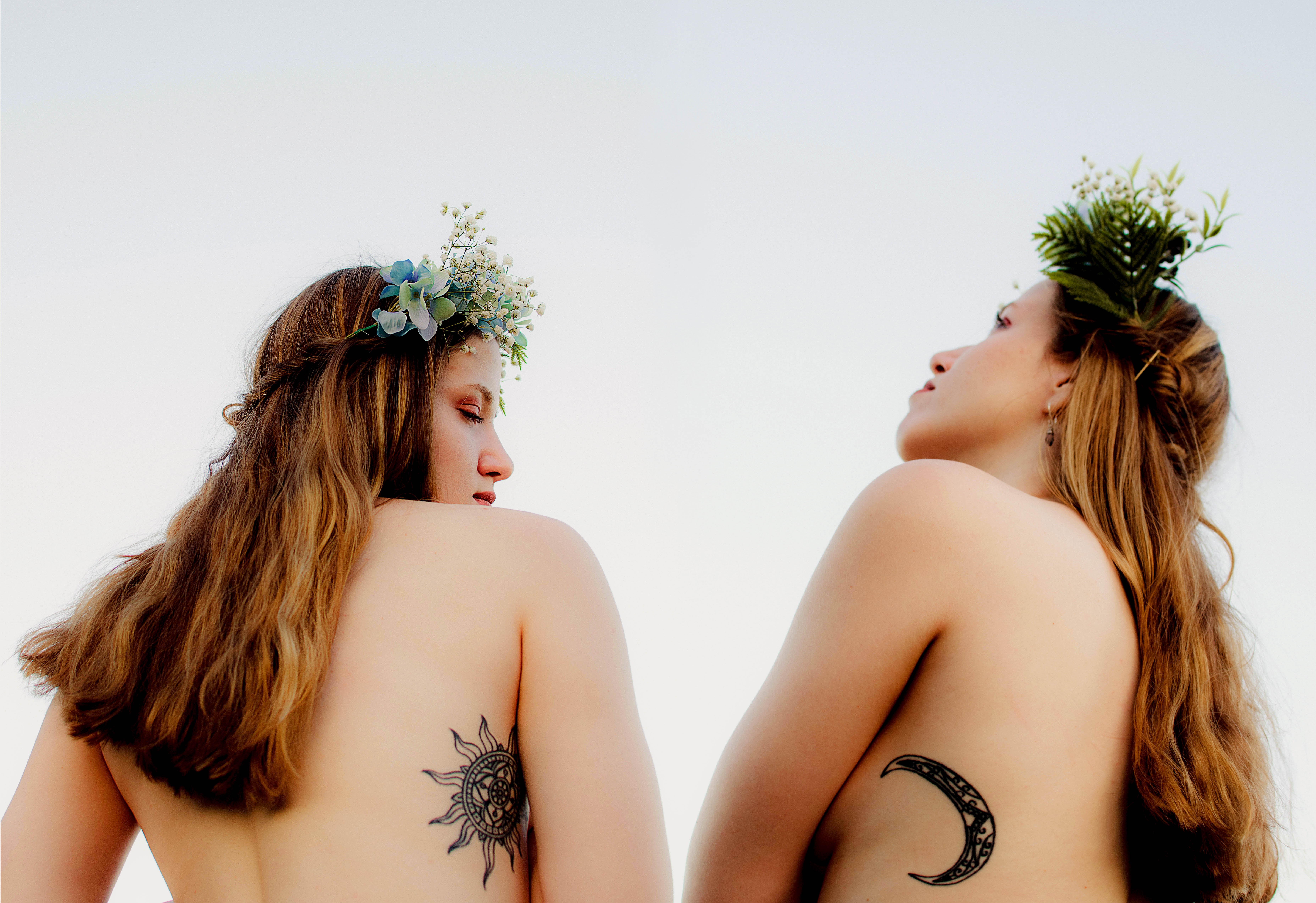 Two women with flower crowns and celestial tattoos HD Wallpaper