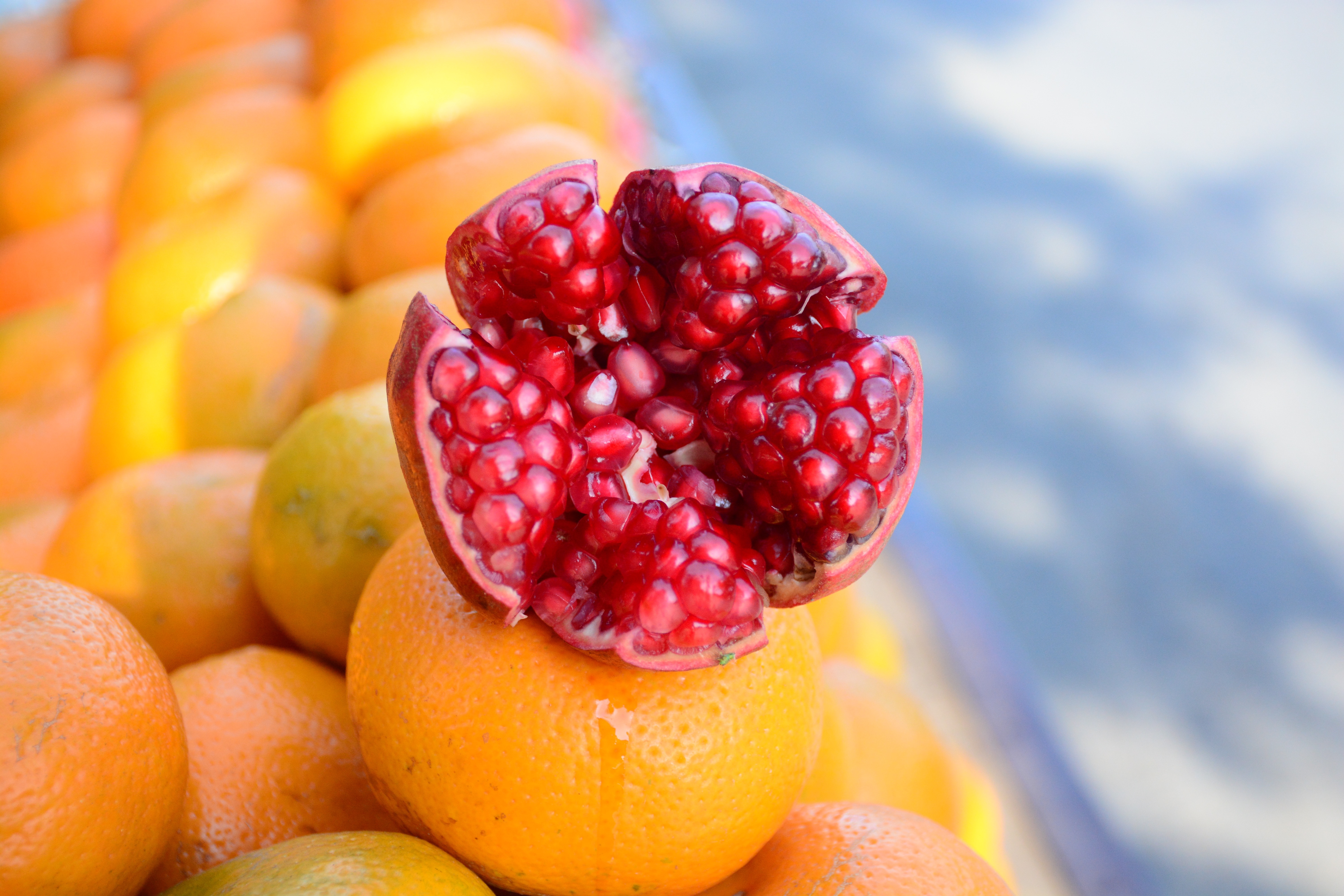 Open pomegranate on top of oranges HD Wallpaper