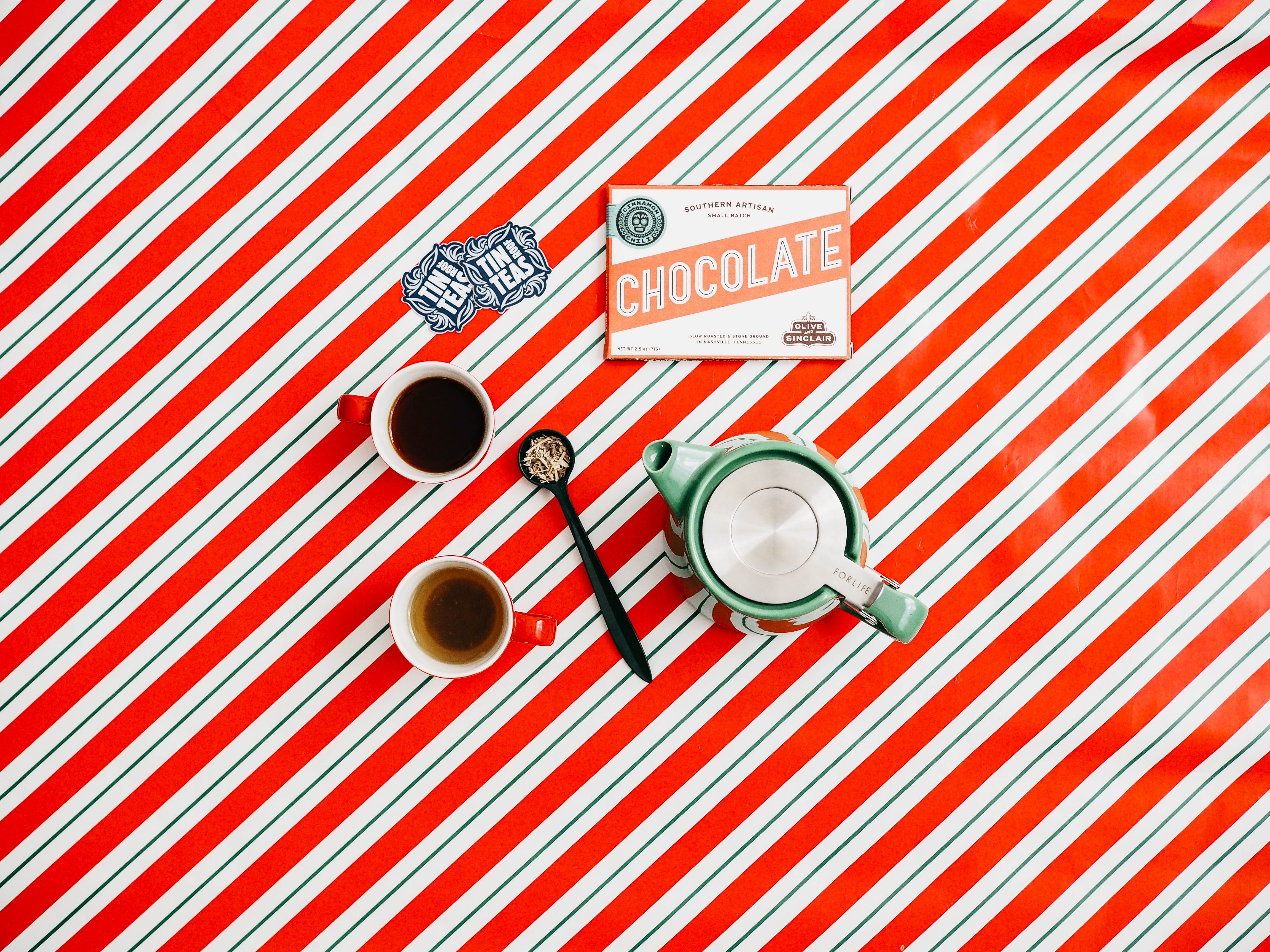 Chocolate bar, cups of tea, and teapot on striped tablecloth HD Wallpaper
