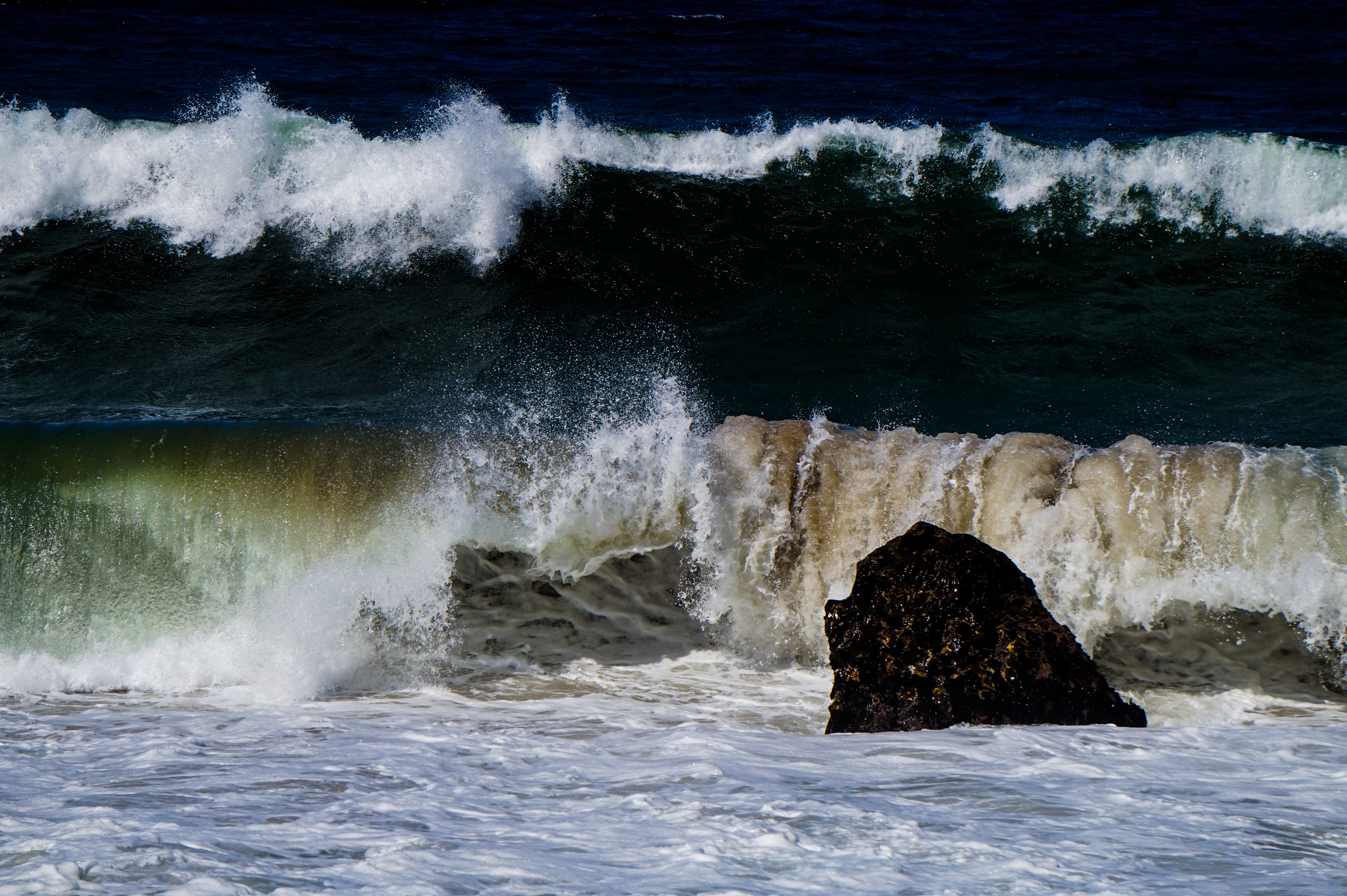 Ocean wave crashing against a large rock HD Wallpaper