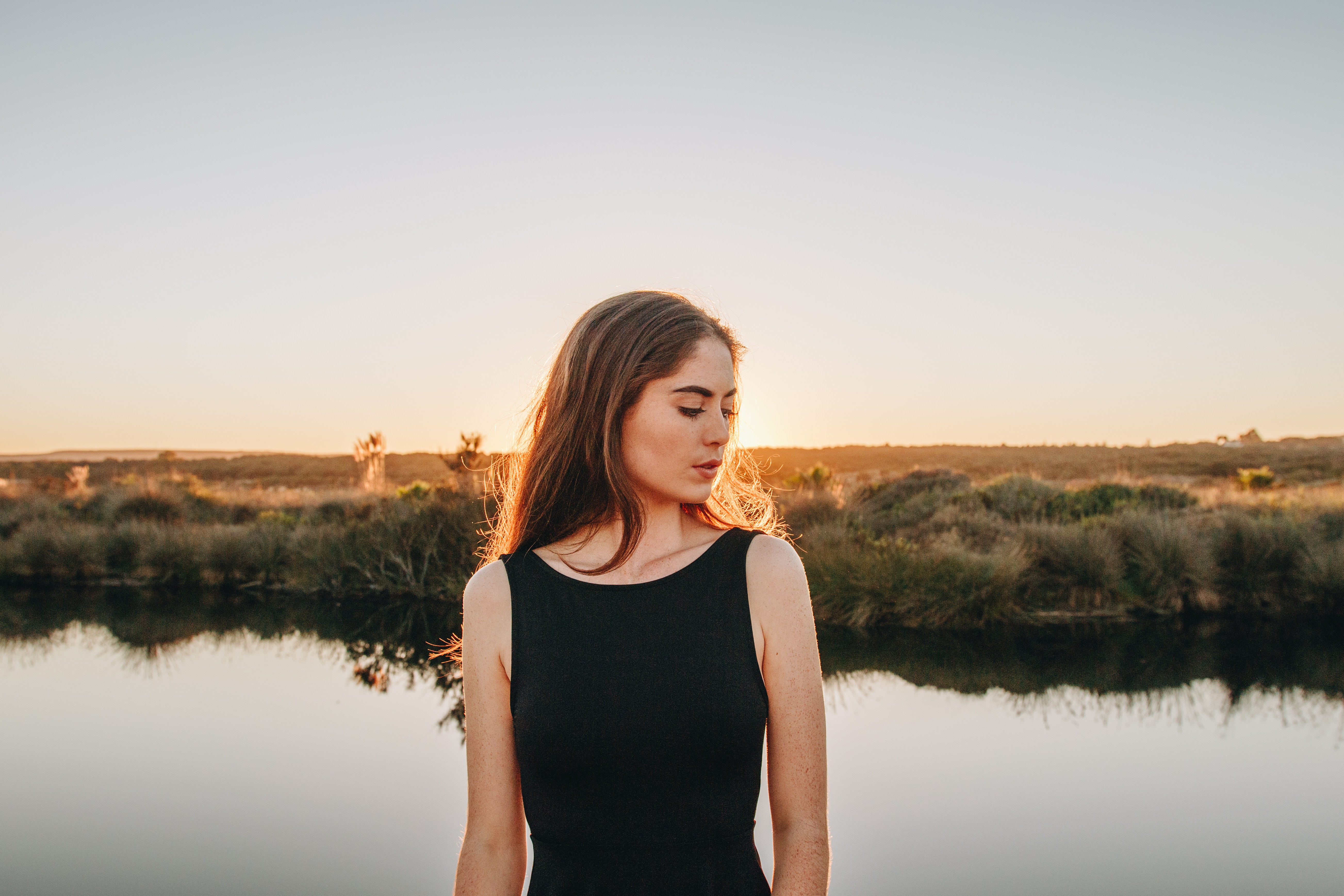Woman in black dress by a lake at sunset HD Wallpaper