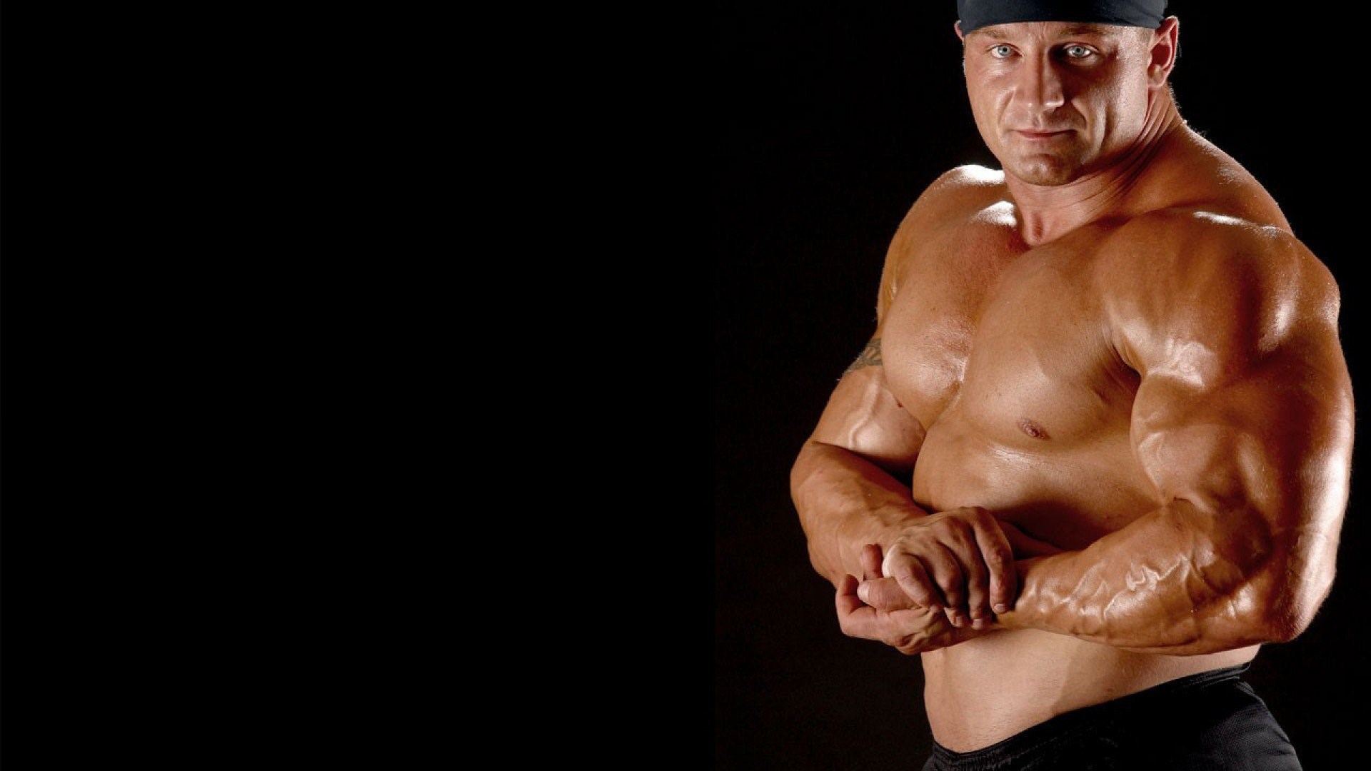 Bodybuilder flexing muscles on black background HD Wallpaper