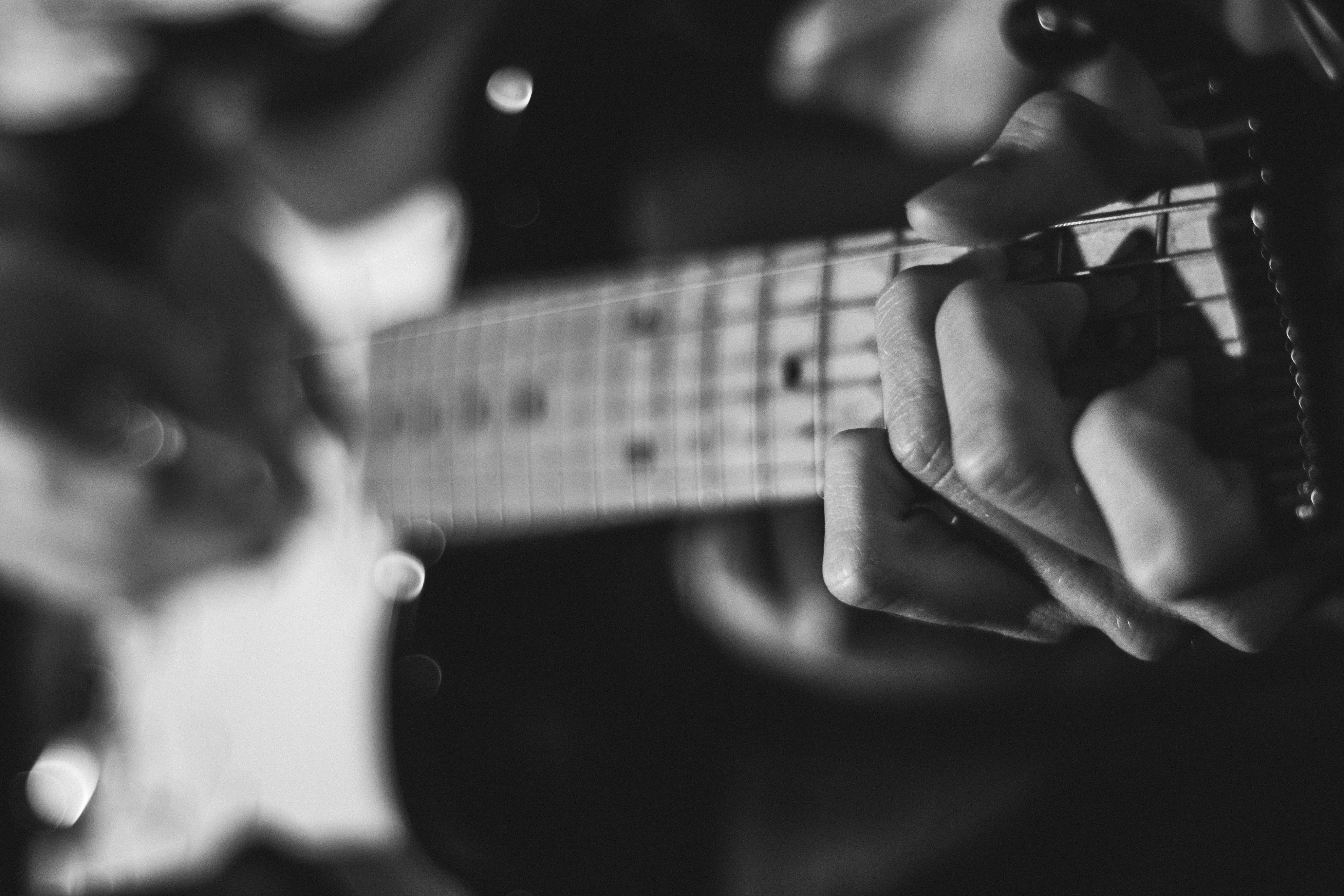 Black and white close-up of hands playing electric guitar HD Wallpaper