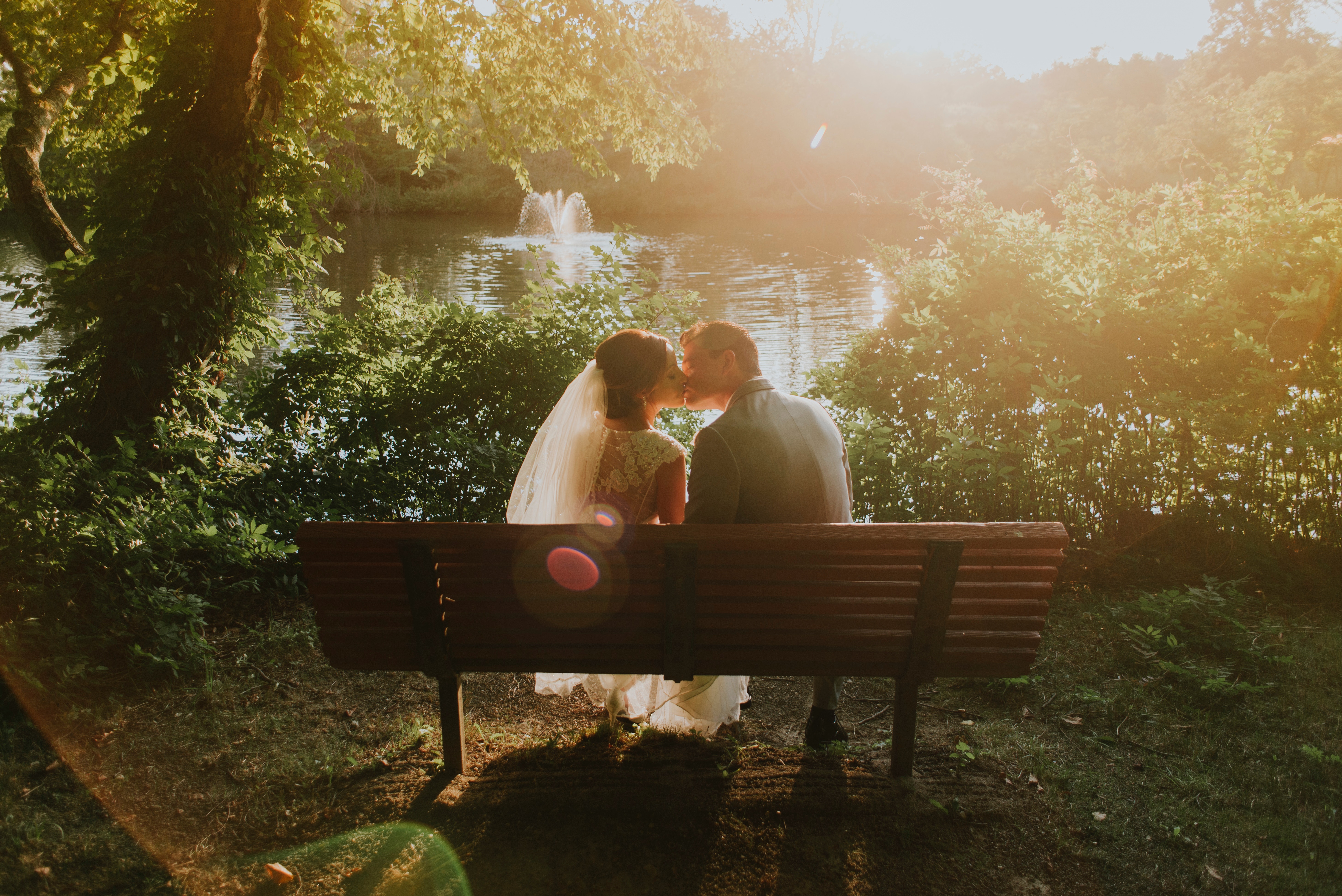 Couple kissing on a park bench by a lake HD Wallpaper
