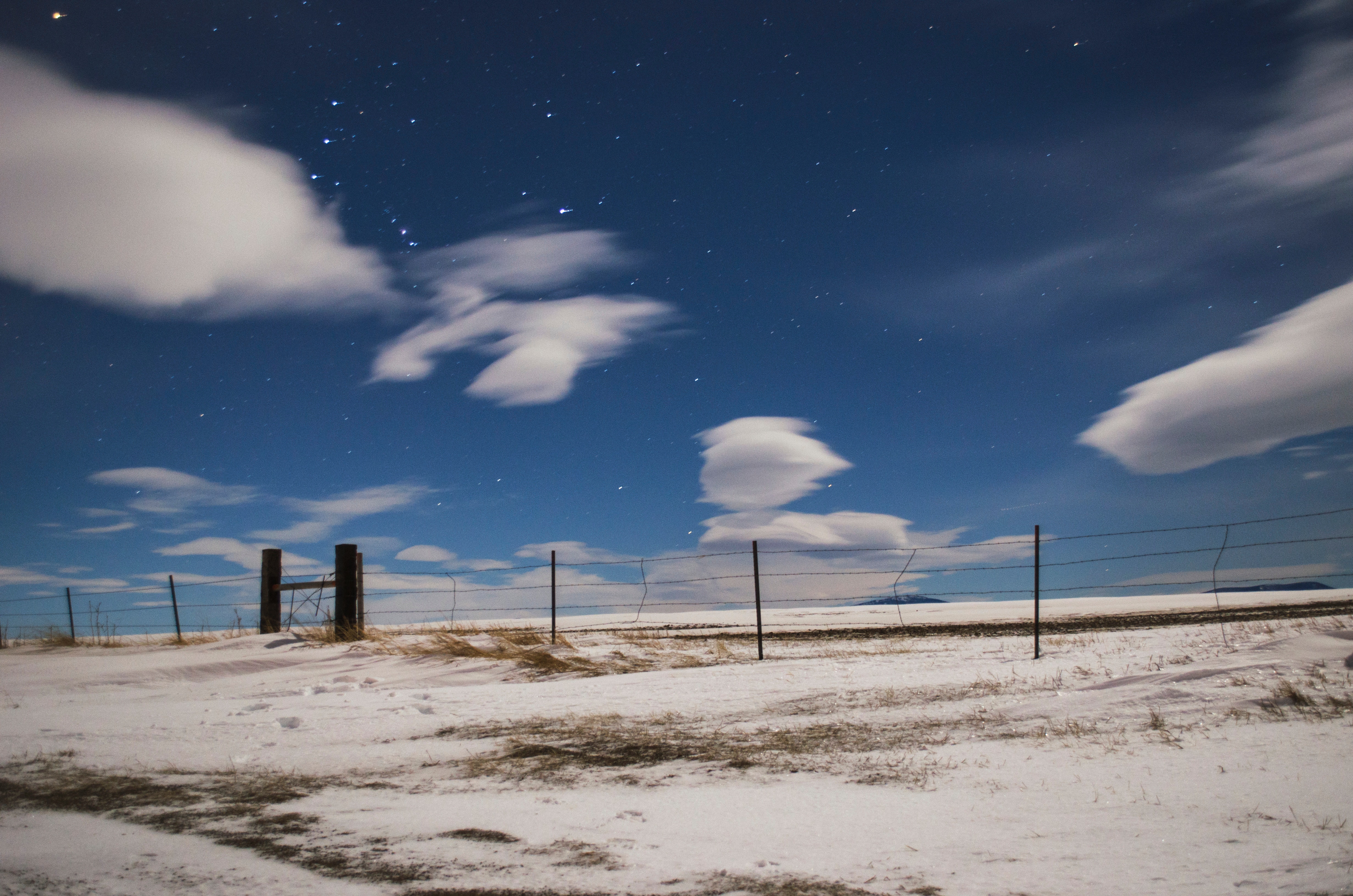 Montana night sky with stars and clouds over a snowy field HD Wallpaper