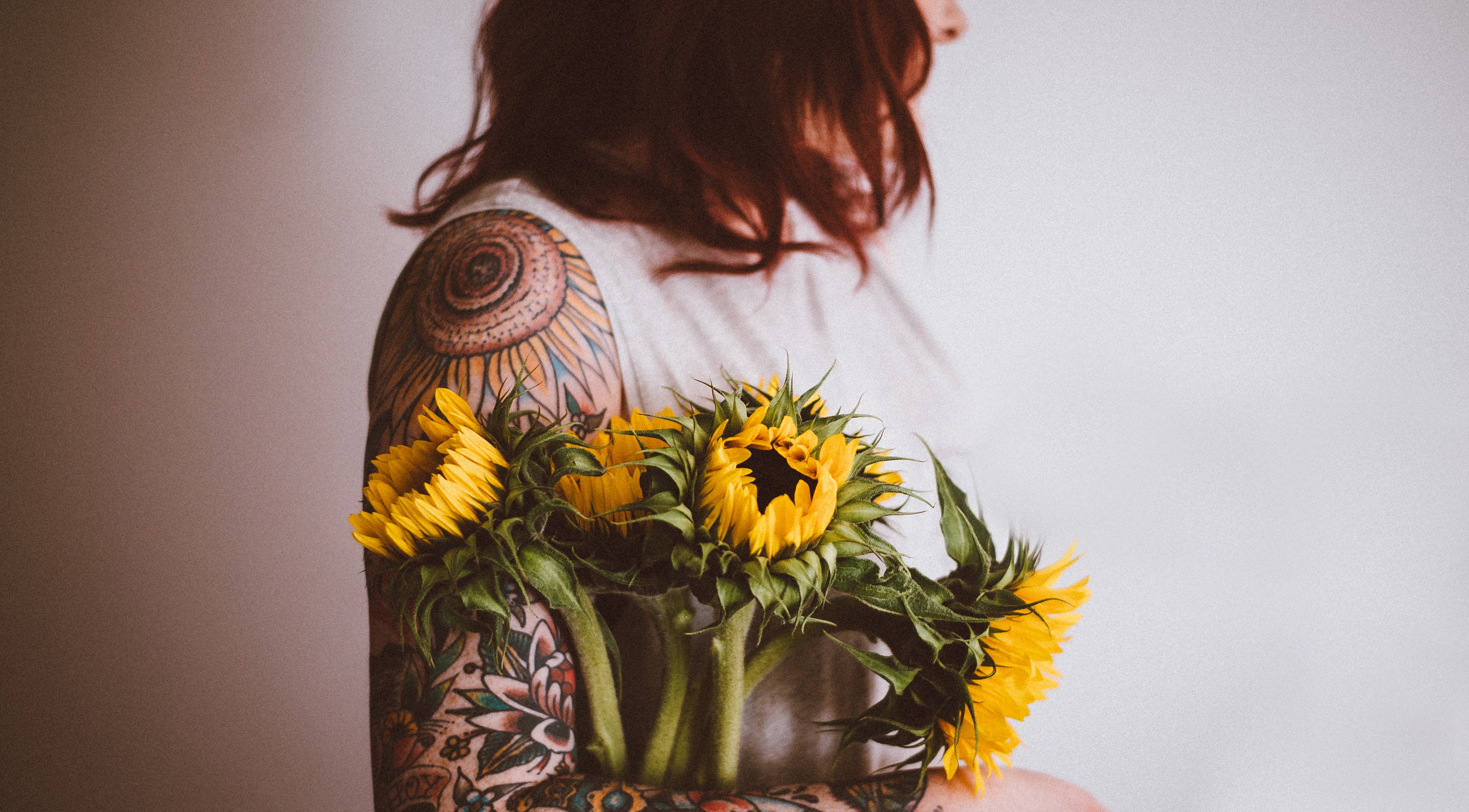 Tattooed woman holding a bouquet of sunflowers HD Wallpaper