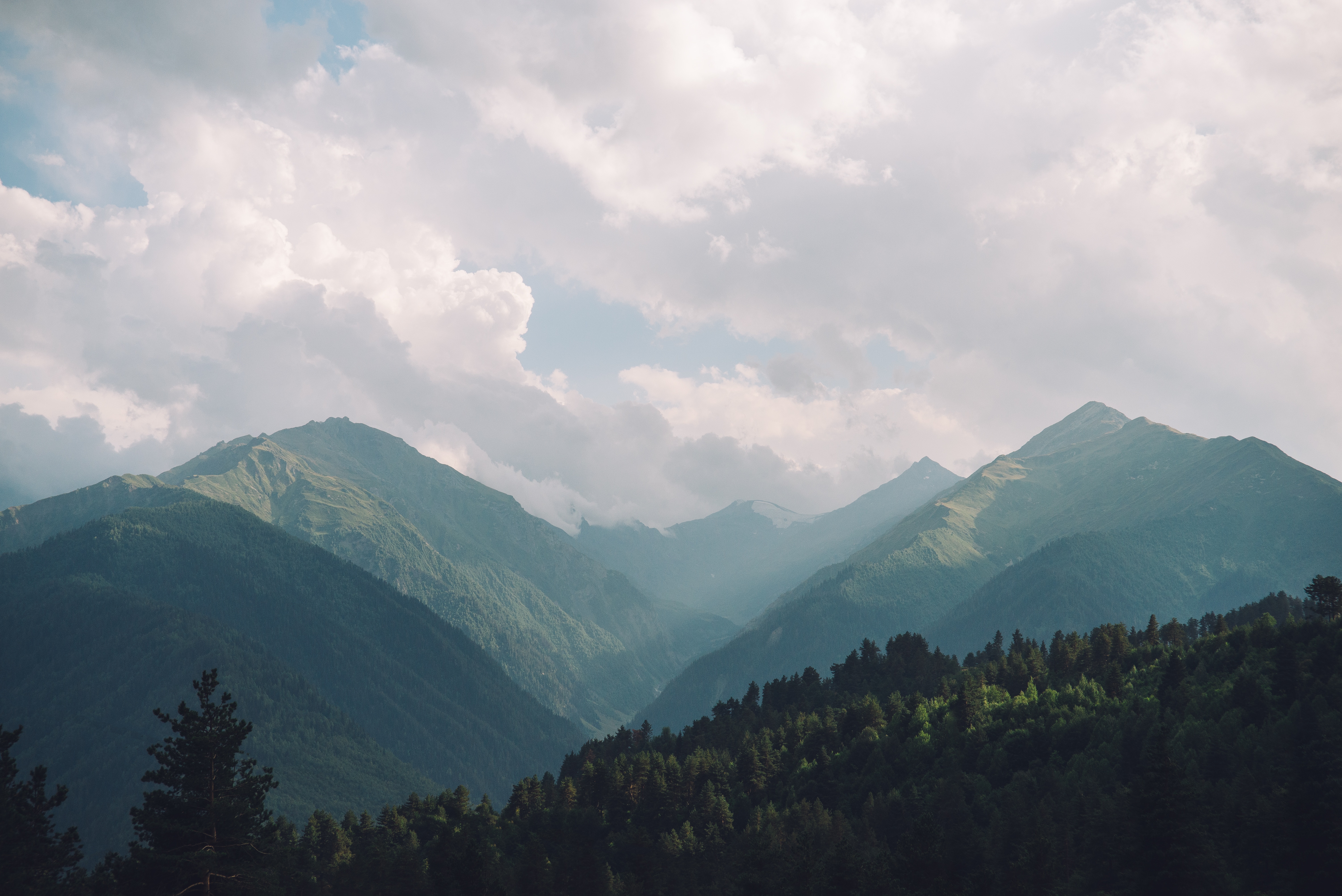 Mountain range with green slopes and cloudy sky HD Wallpaper