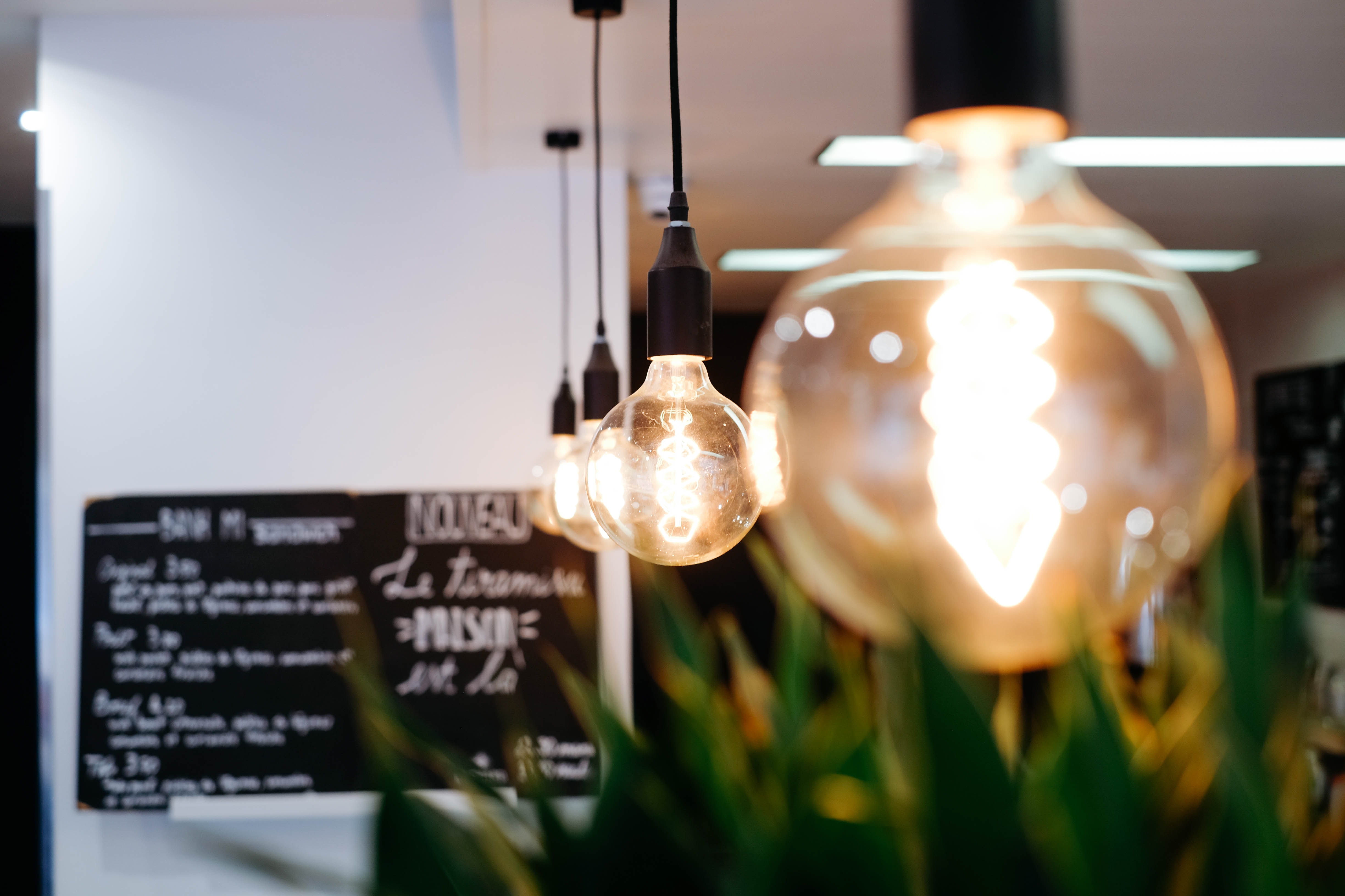 Restaurant interior with hanging Edison bulbs and menu HD Wallpaper