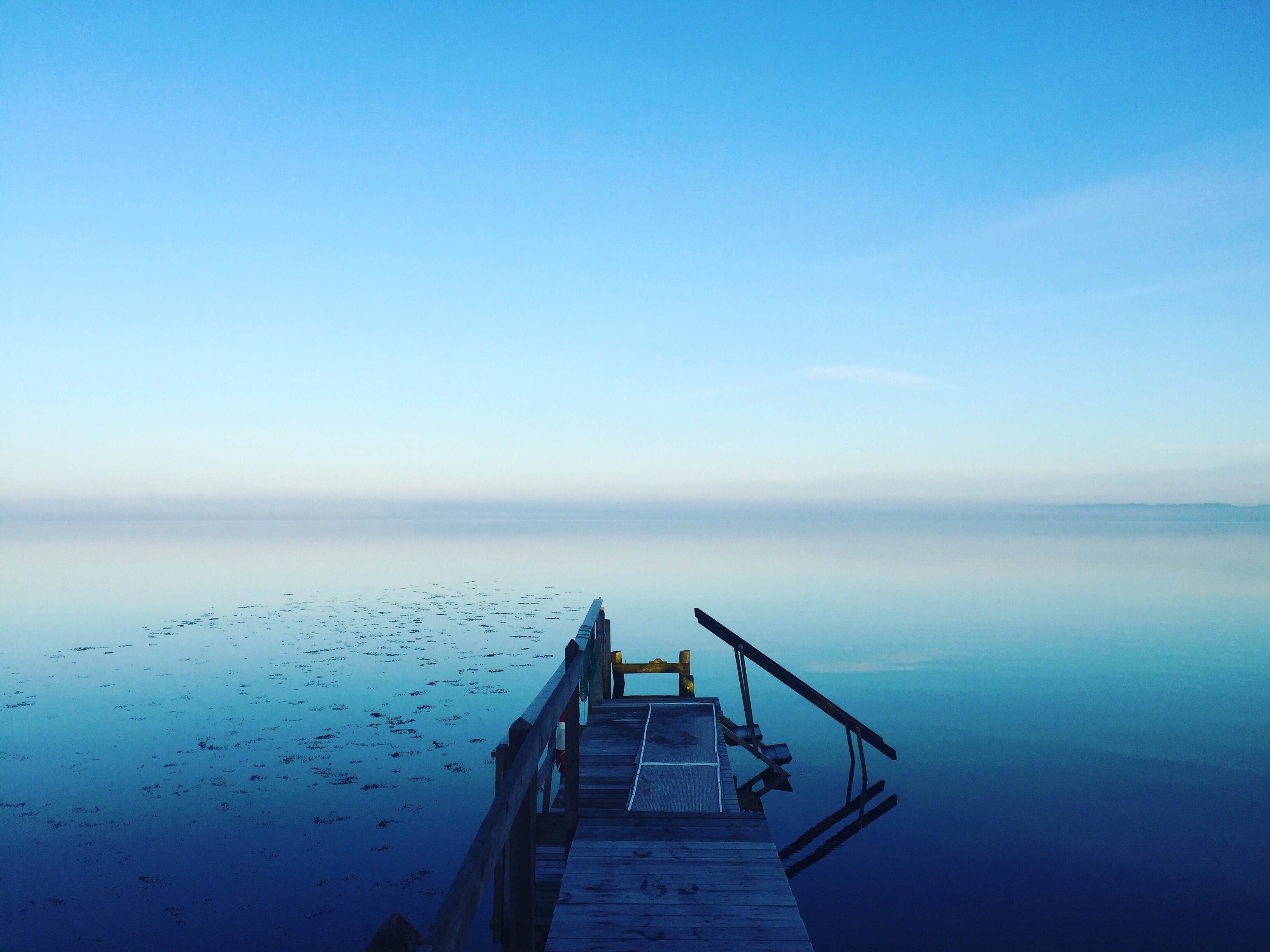 Wooden dock on a calm lake at dawn HD Wallpaper