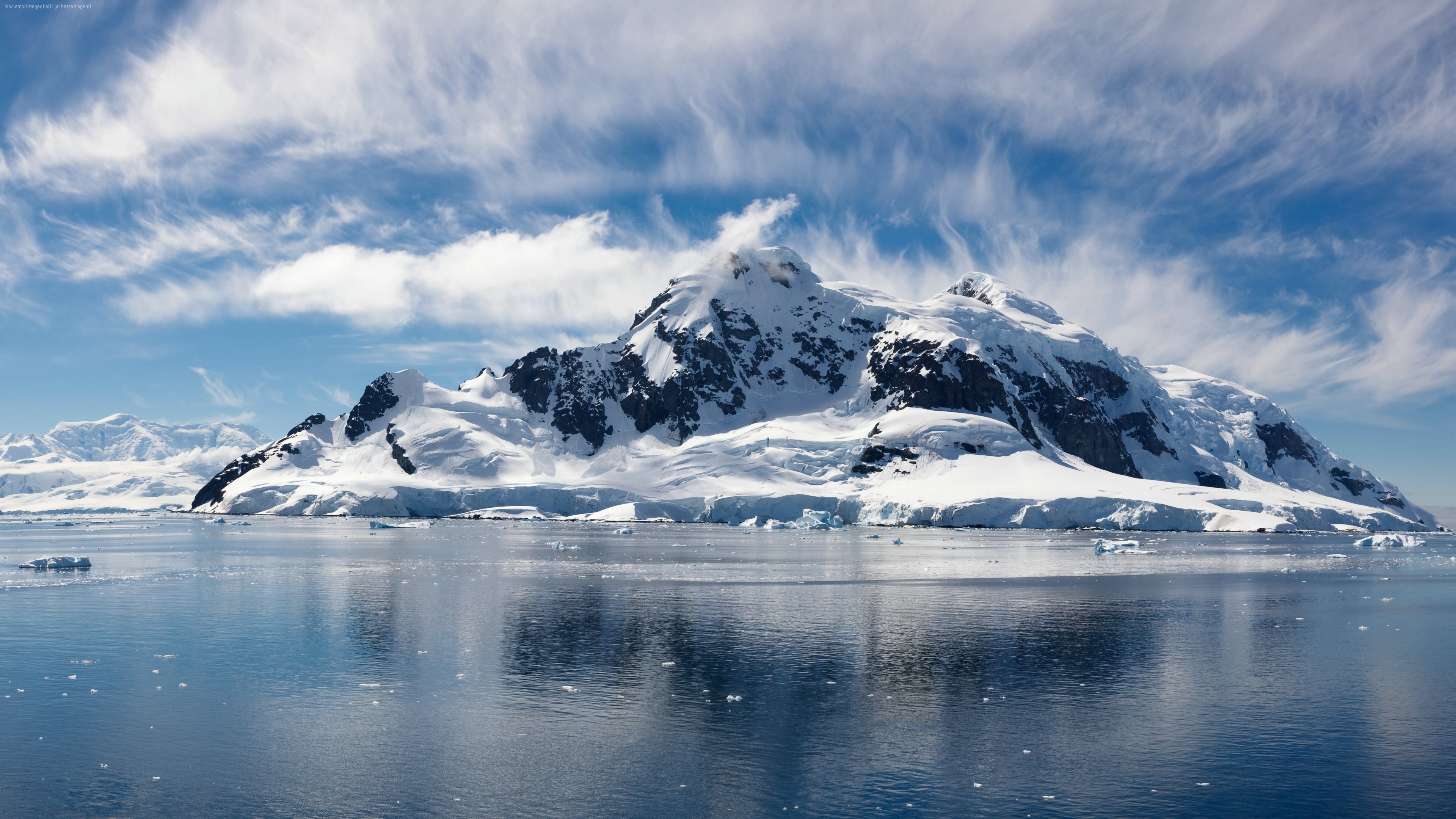 Snow-covered mountains and islands in the ocean under a cloudy sky HD Wallpaper