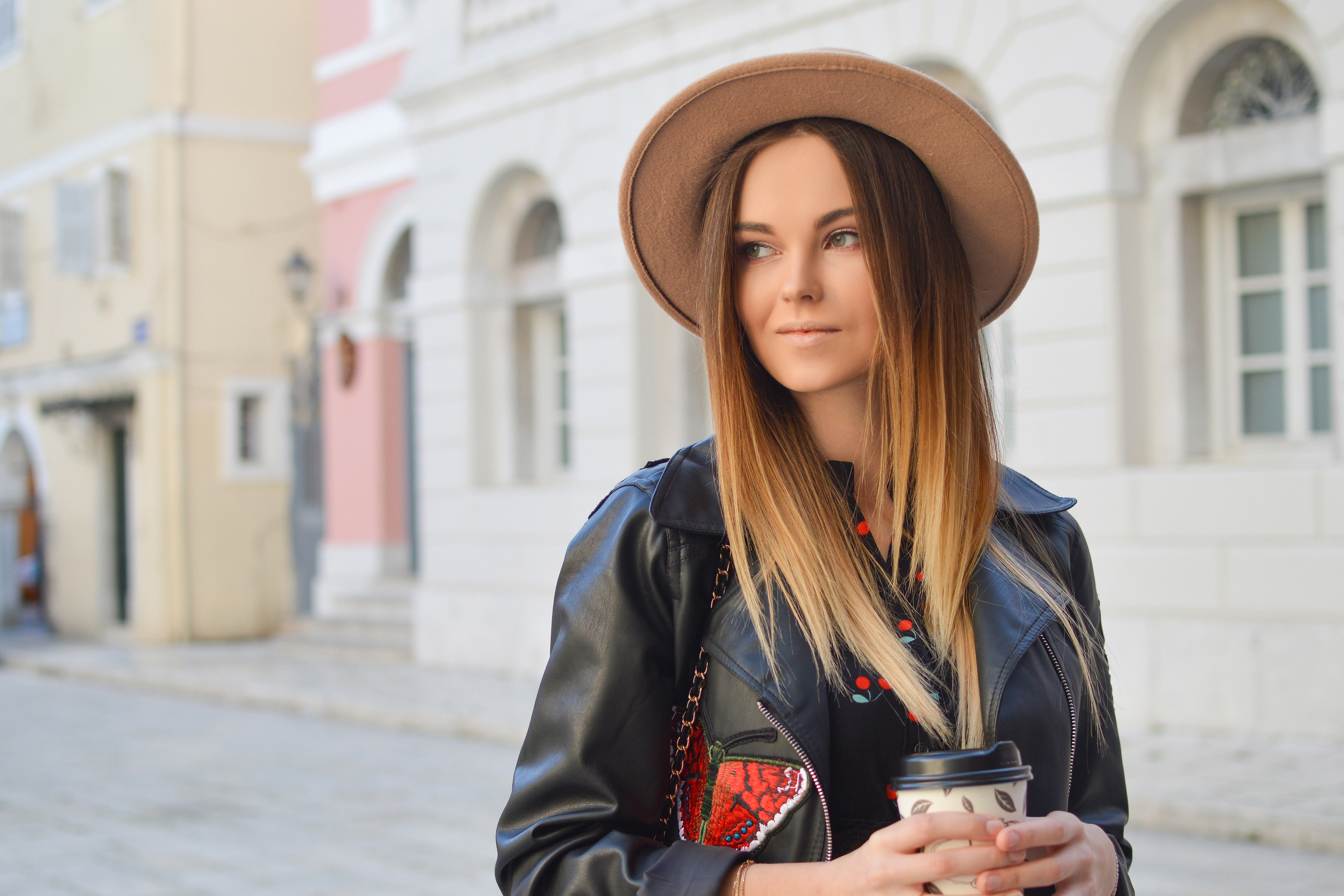 Woman in hat and leather jacket holding coffee cup in city HD Wallpaper