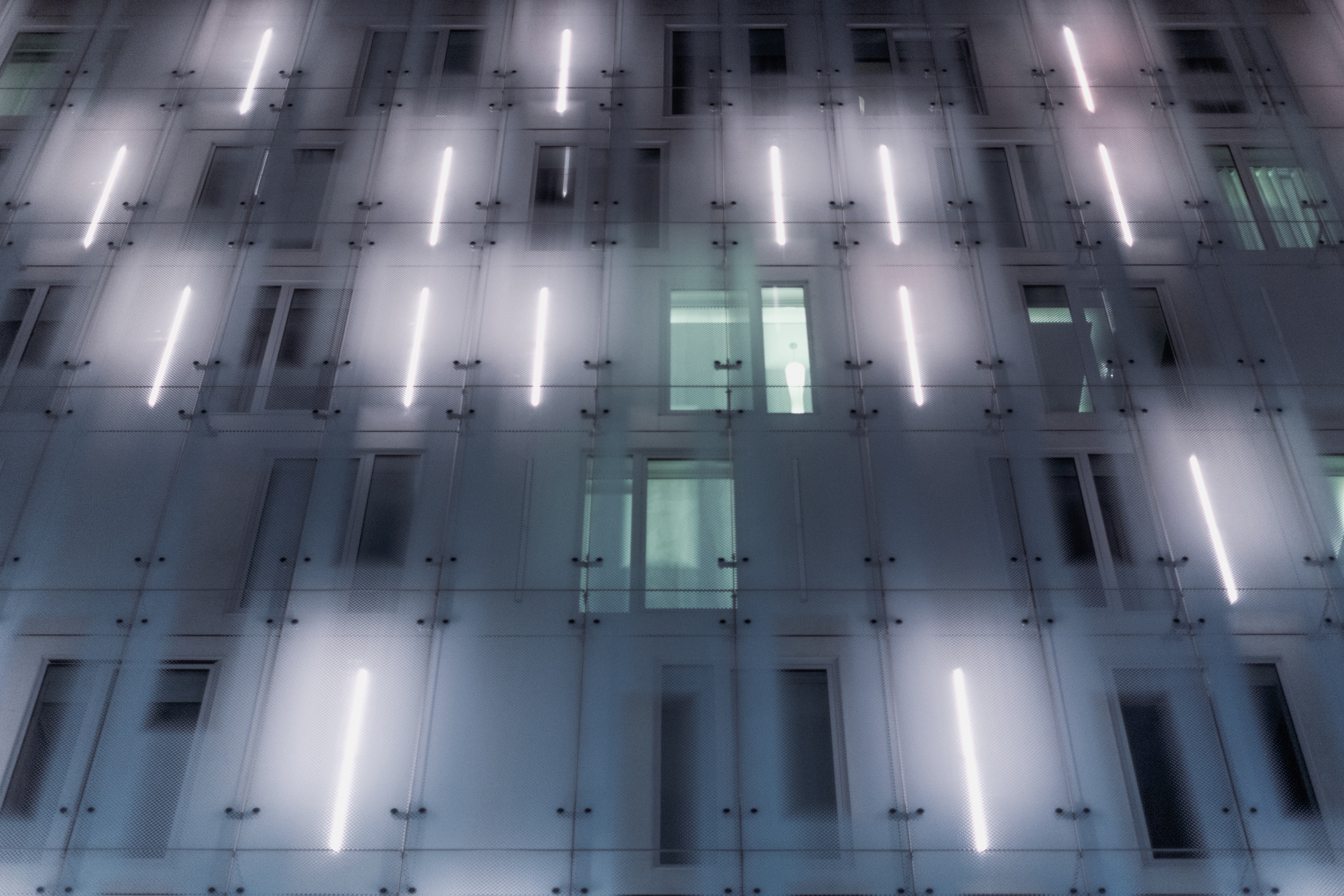 Modern building facade with glowing lights at night HD Wallpaper
