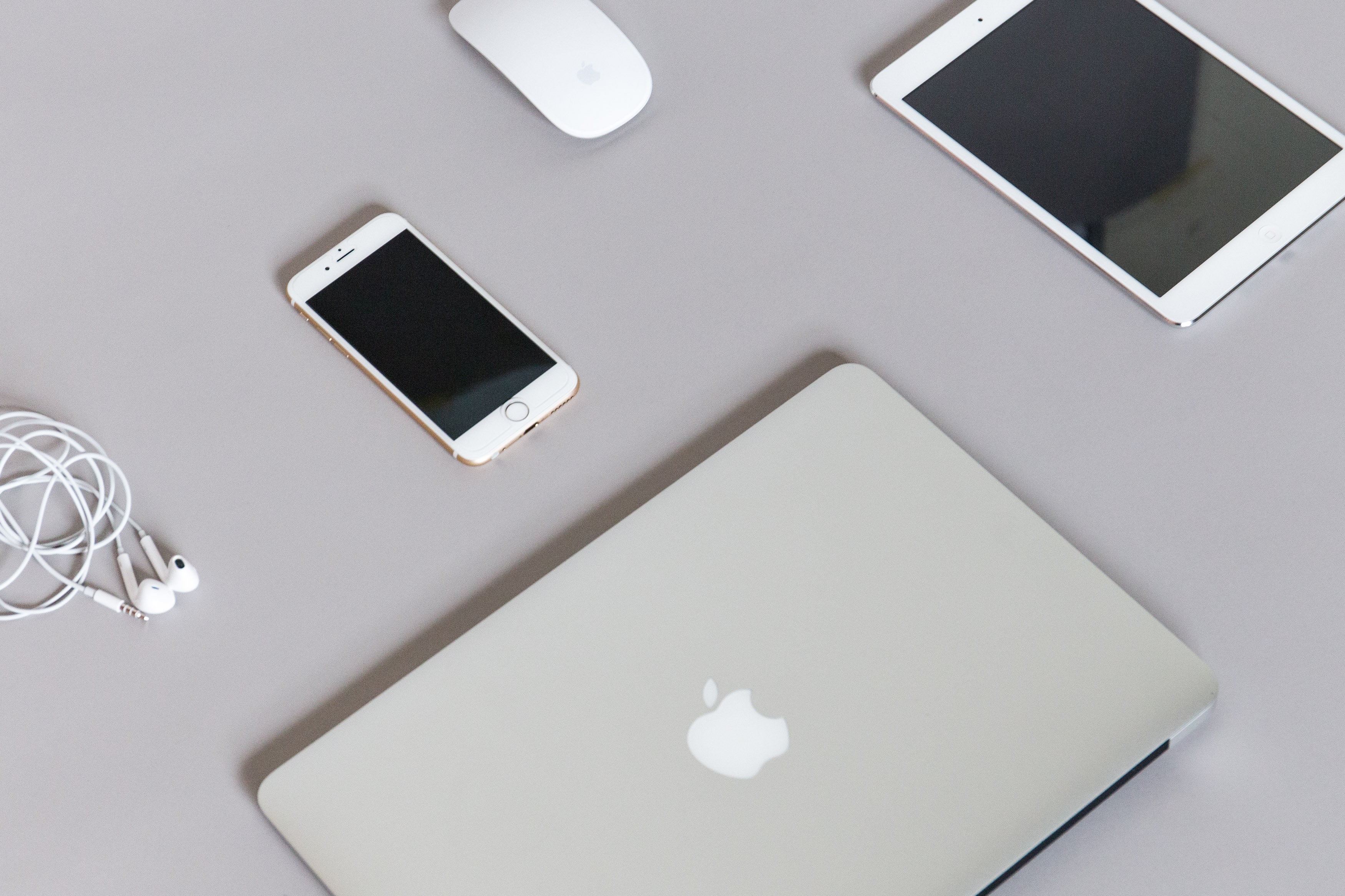 Apple Laptop, Tablet, Smartphone, Mouse, and Earbuds on Gray Surface HD Wallpaper
