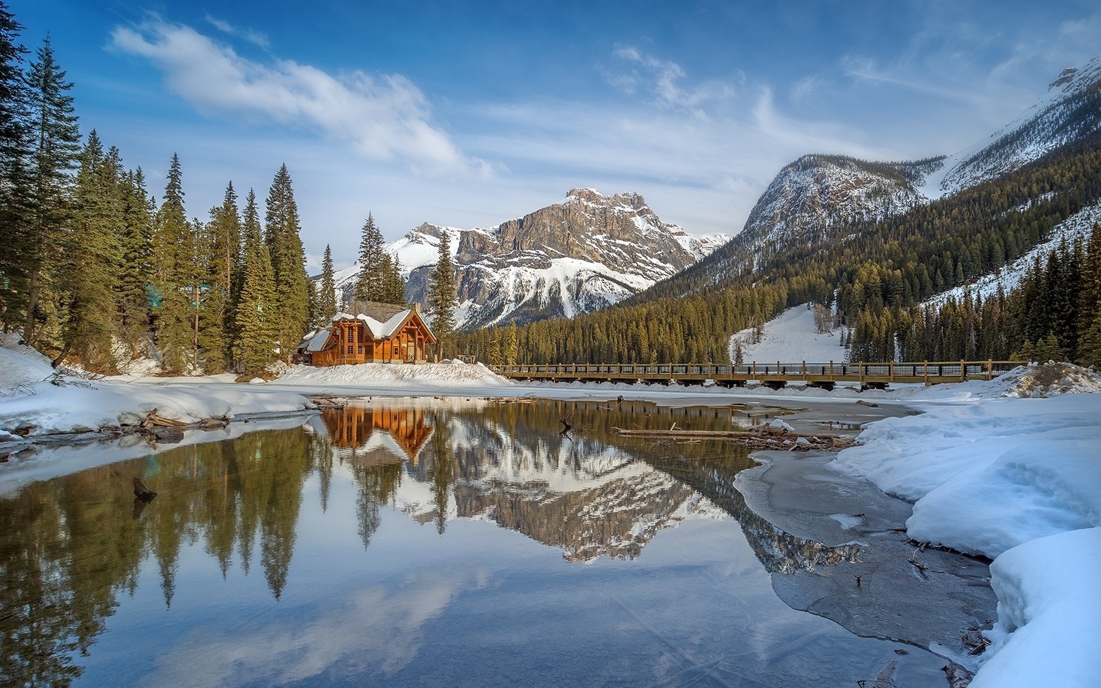 Winter cabin by a lake with snow-capped mountains HD Wallpaper