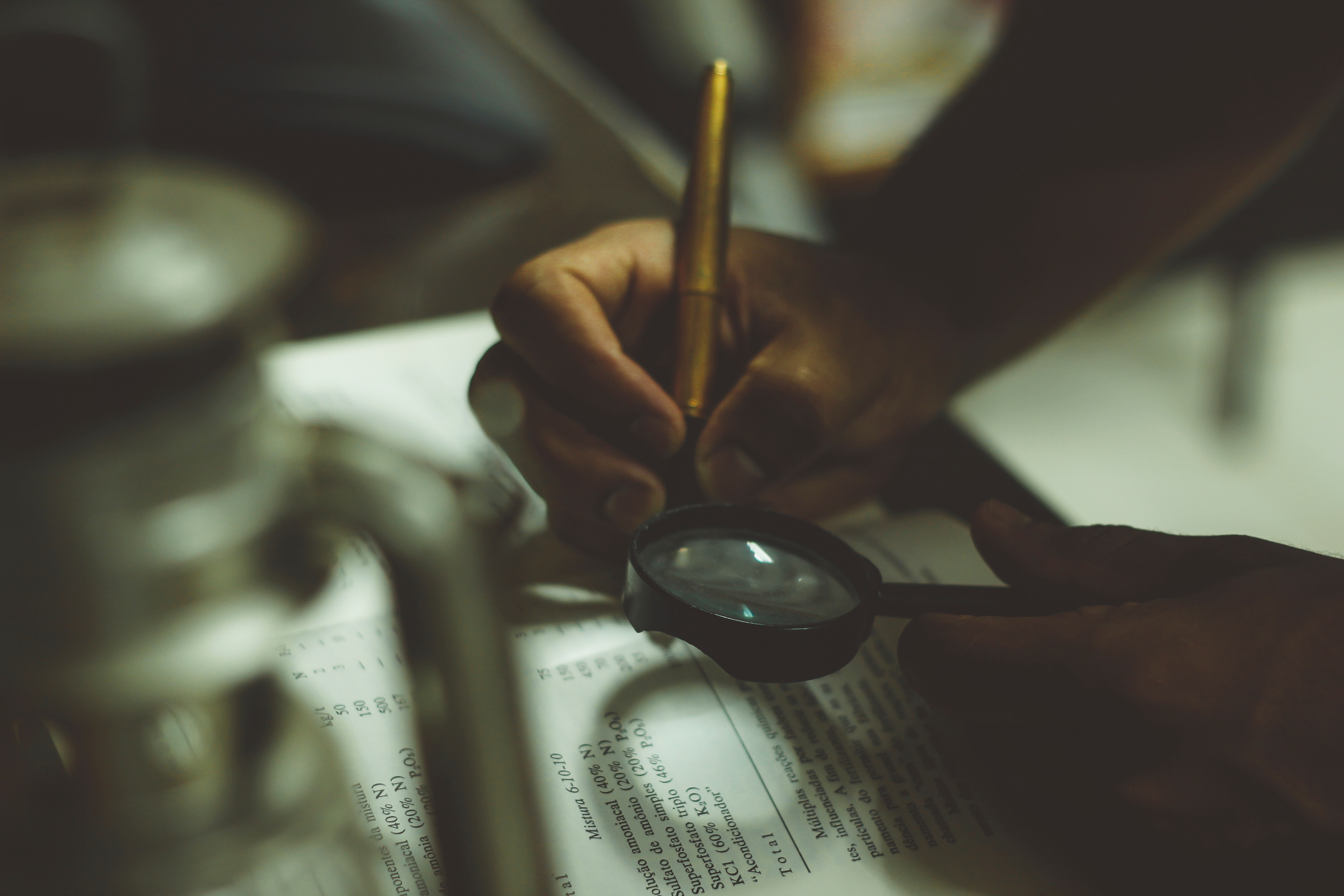 Person writing with magnifying glass HD Wallpaper