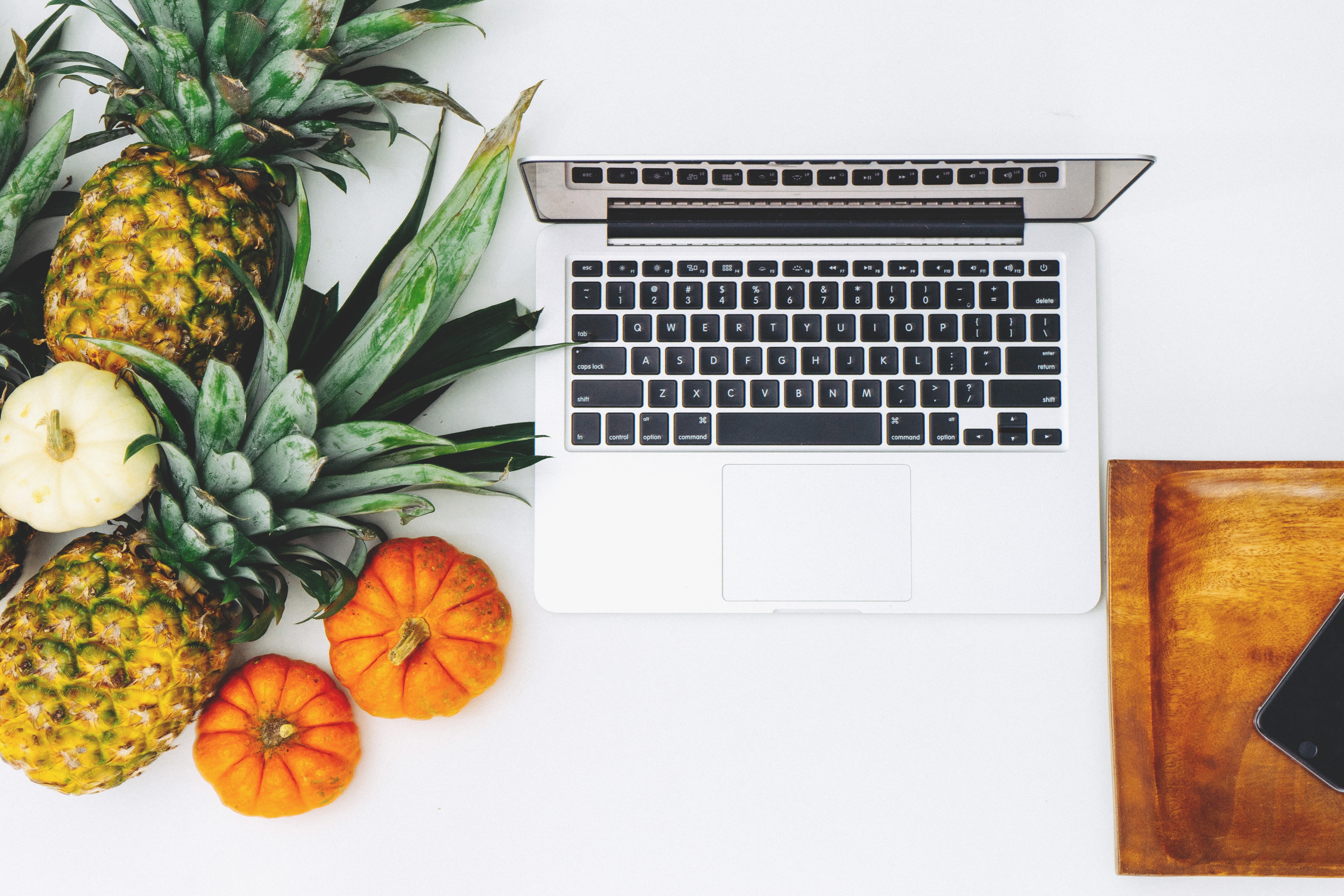 Flatlay of pineapples, pumpkins, and a laptop HD Wallpaper