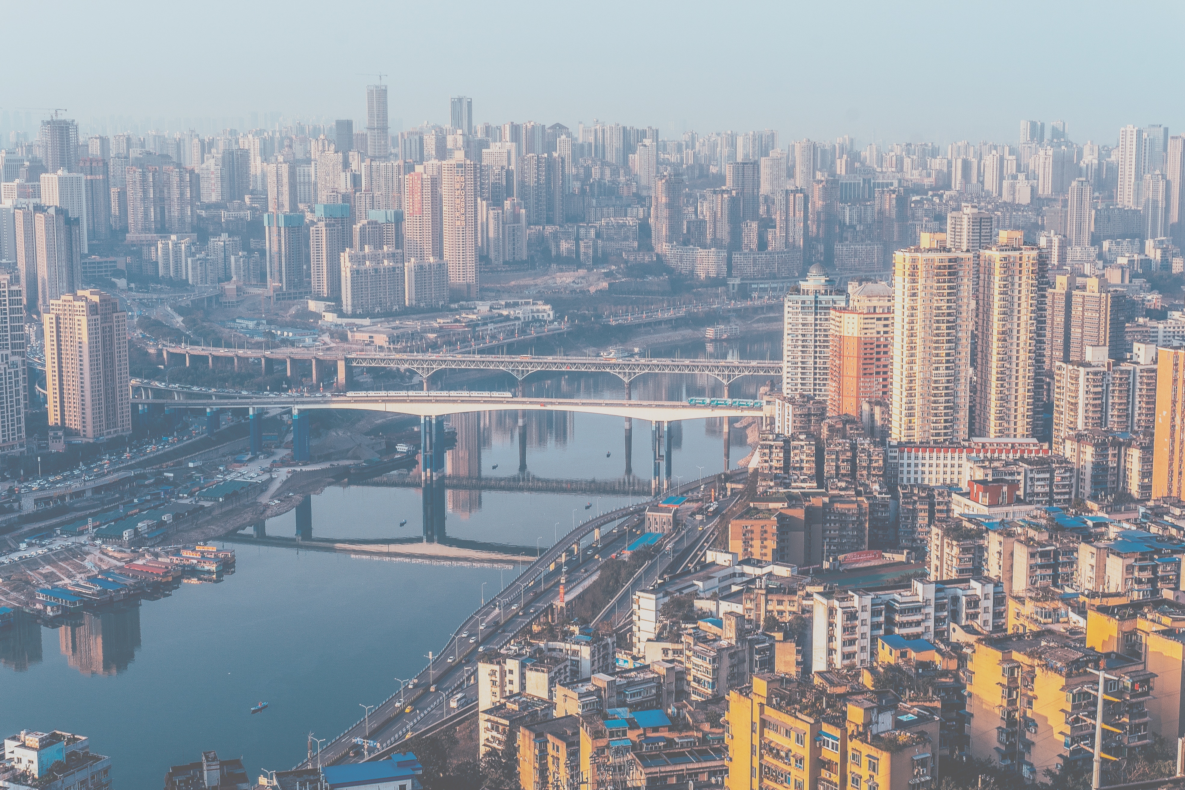 Aerial view of a sprawling city with skyscrapers and bridges over a river in China HD Wallpaper