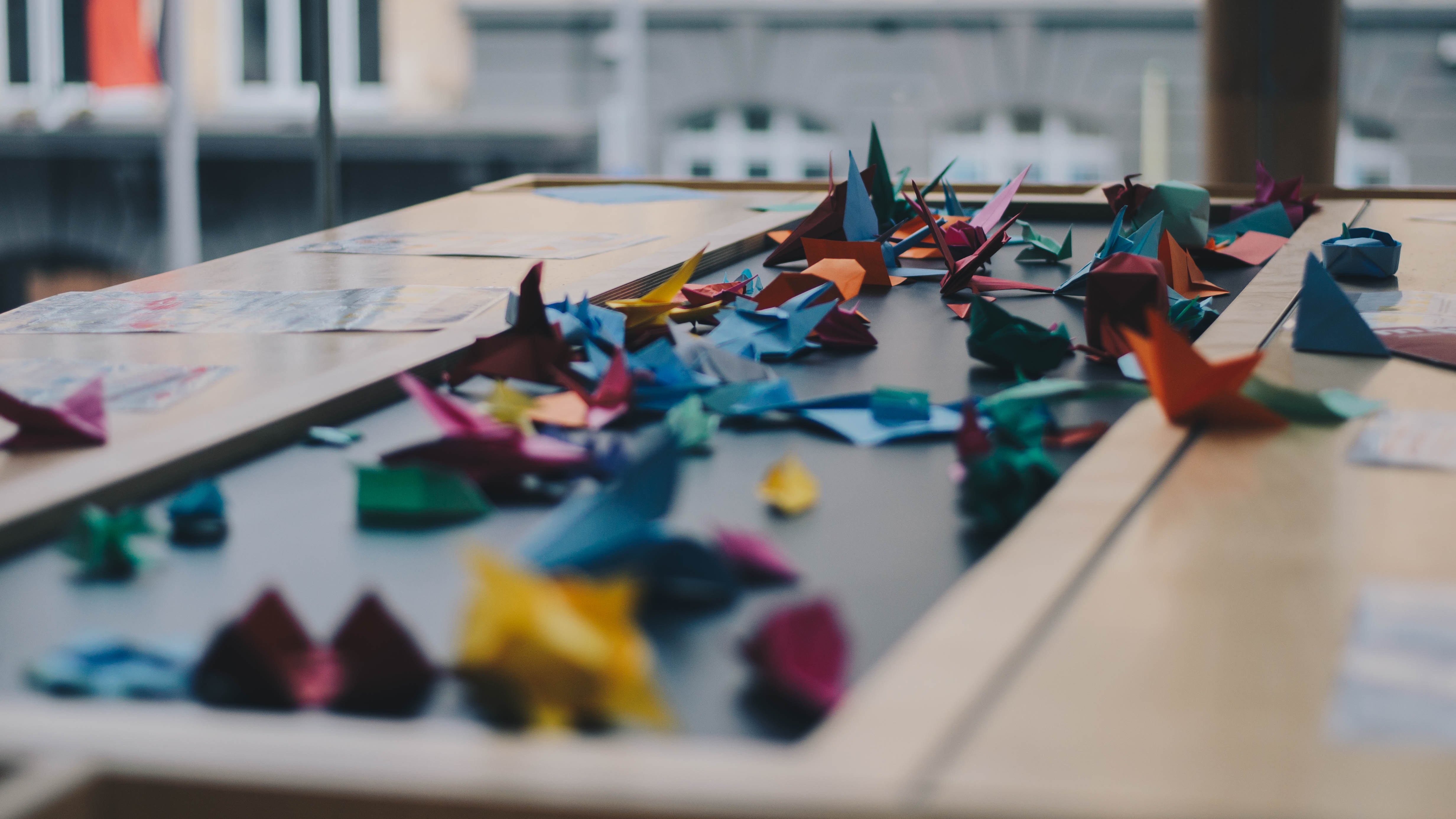Colorful origami cranes scattered on a table HD Wallpaper