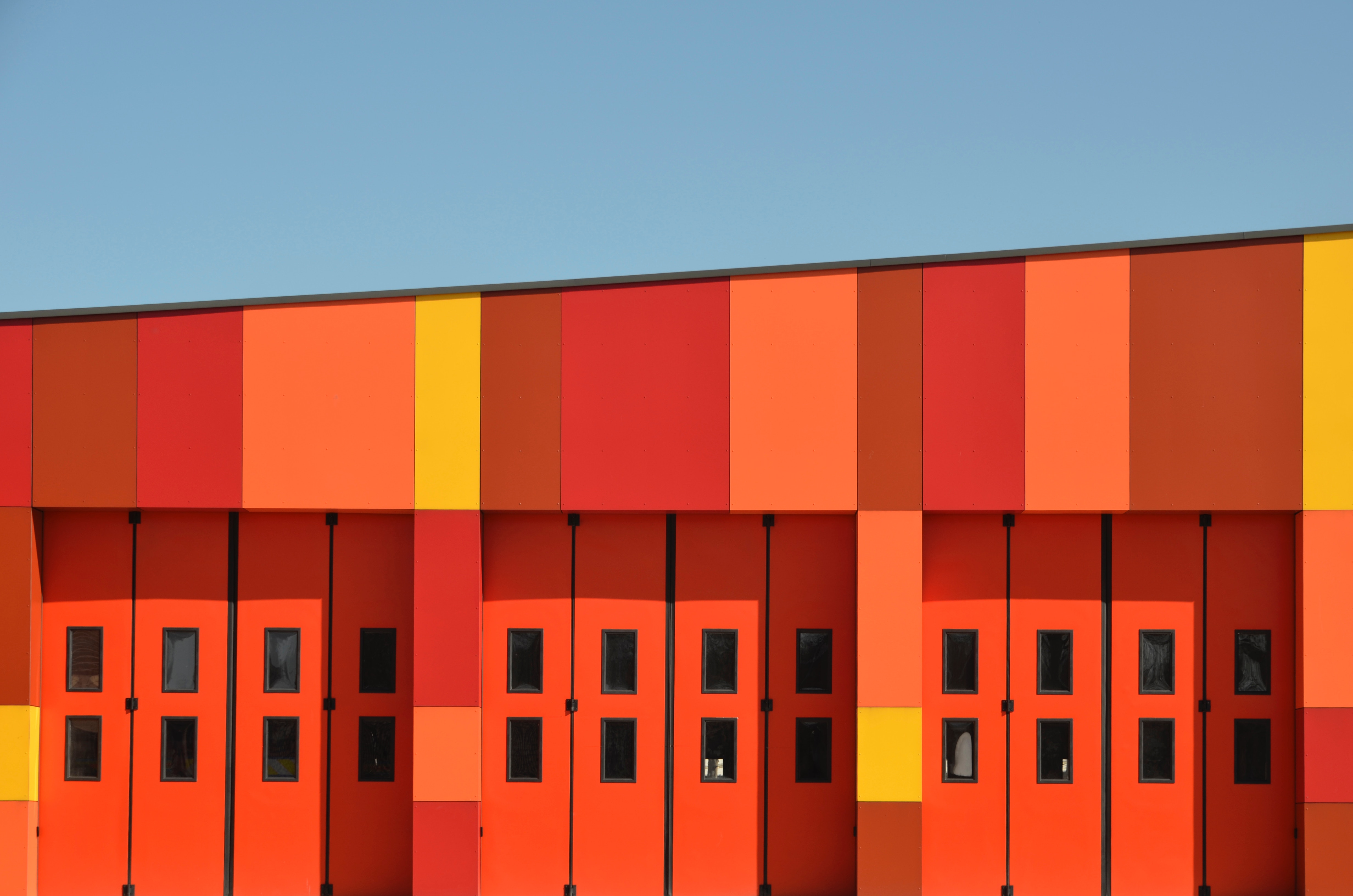 Colorful building with garage doors and blue sky HD Wallpaper