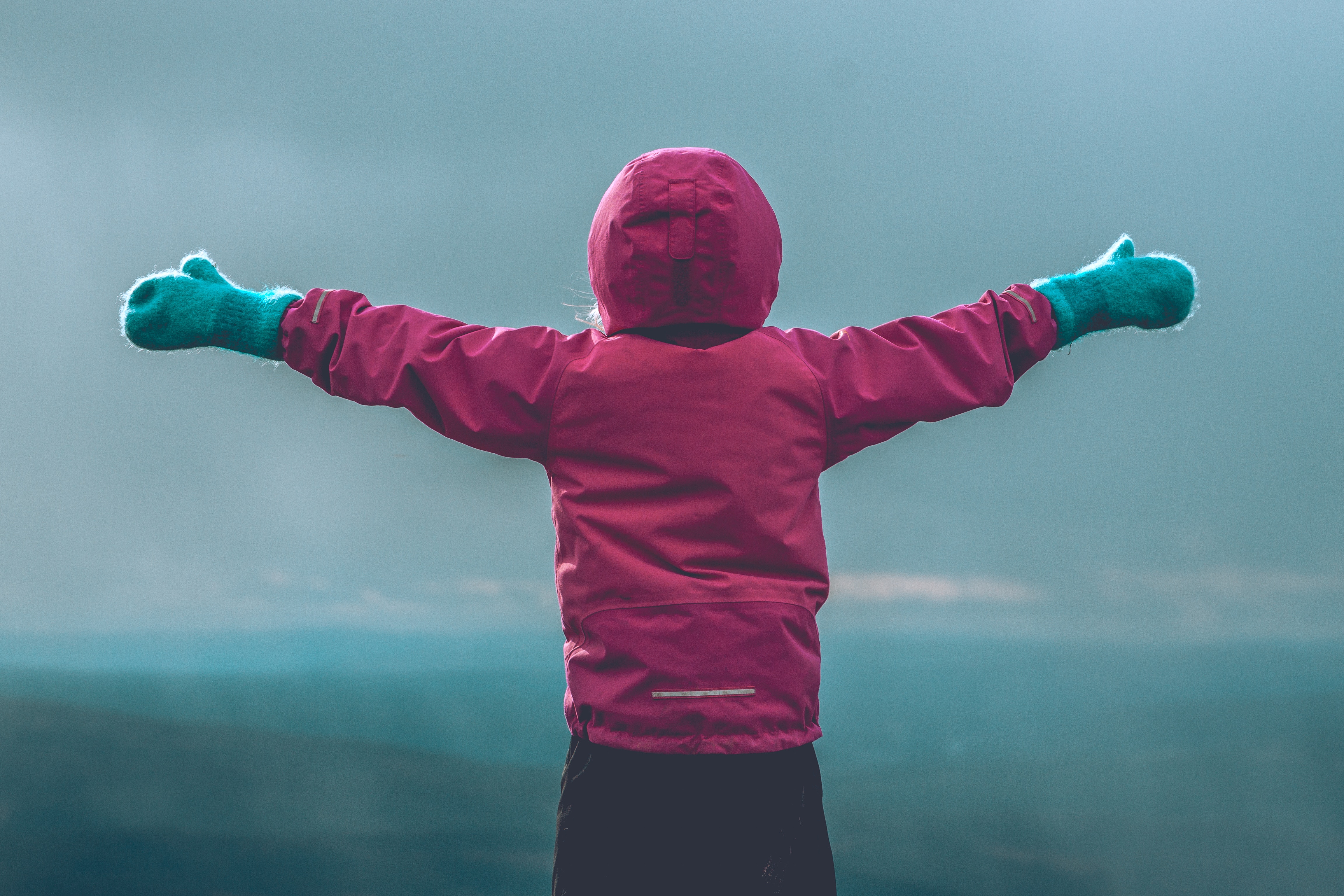 Girl in pink jacket with arms spread wide HD Wallpaper