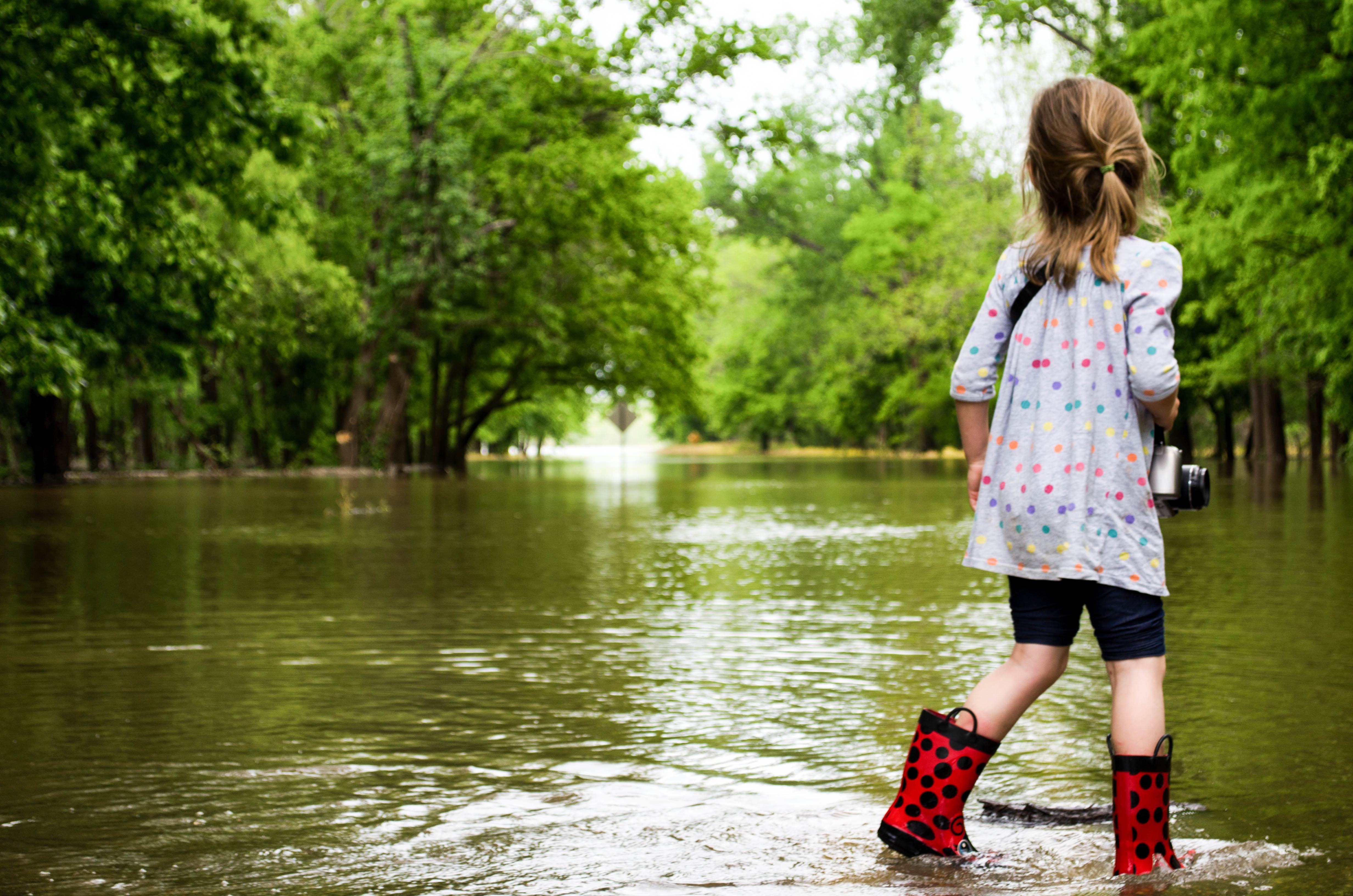 Girl in red boots wading through floodwaters HD Wallpaper